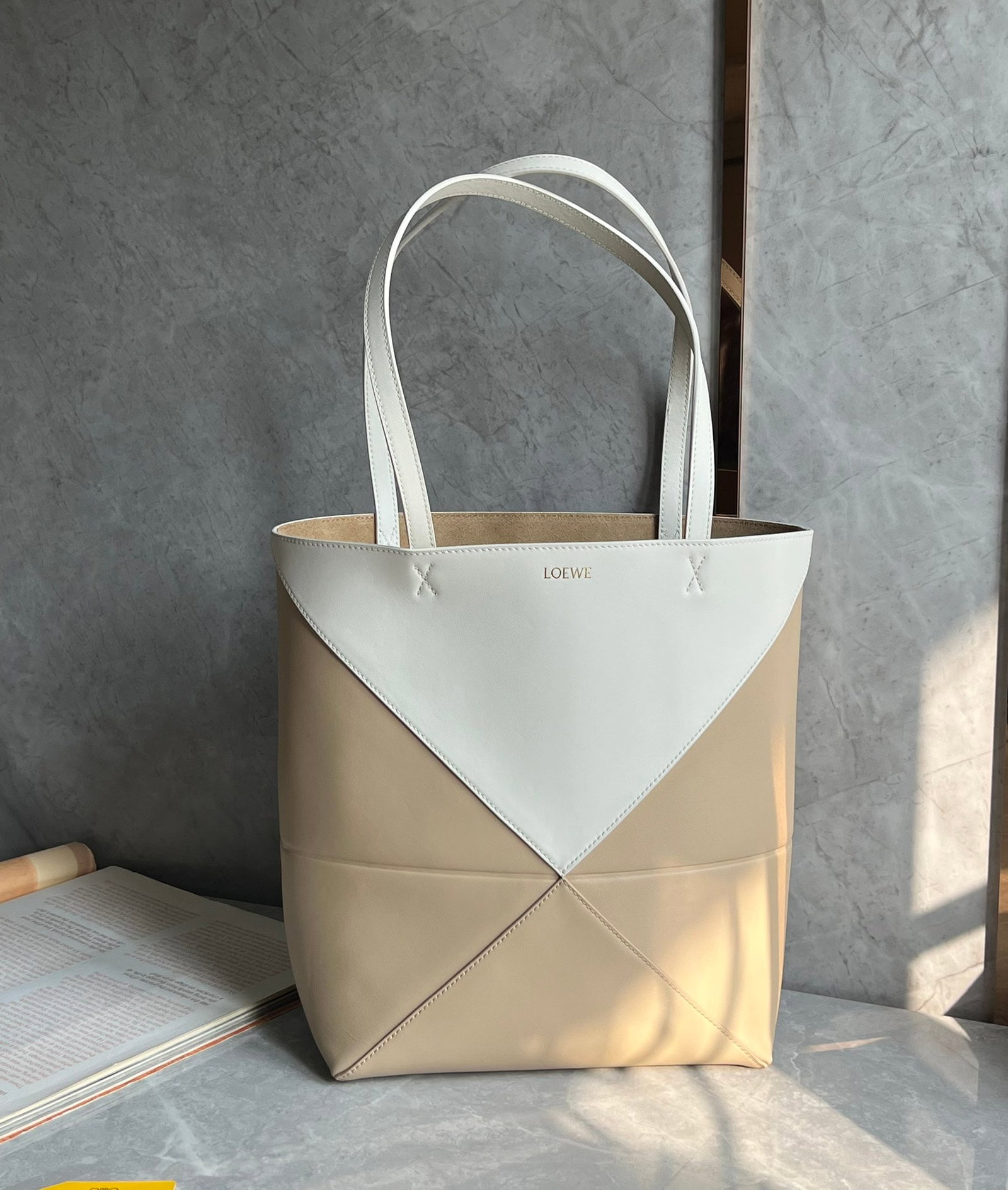 LOEWE: The LOEWE Puzzle Fold Tote bag features a trendy milk tea color-block design. Made of Nappa calfskin, the Puzzle Fold Tote boasts clean lines inspired by origami, exuding a subtle and understated eleg