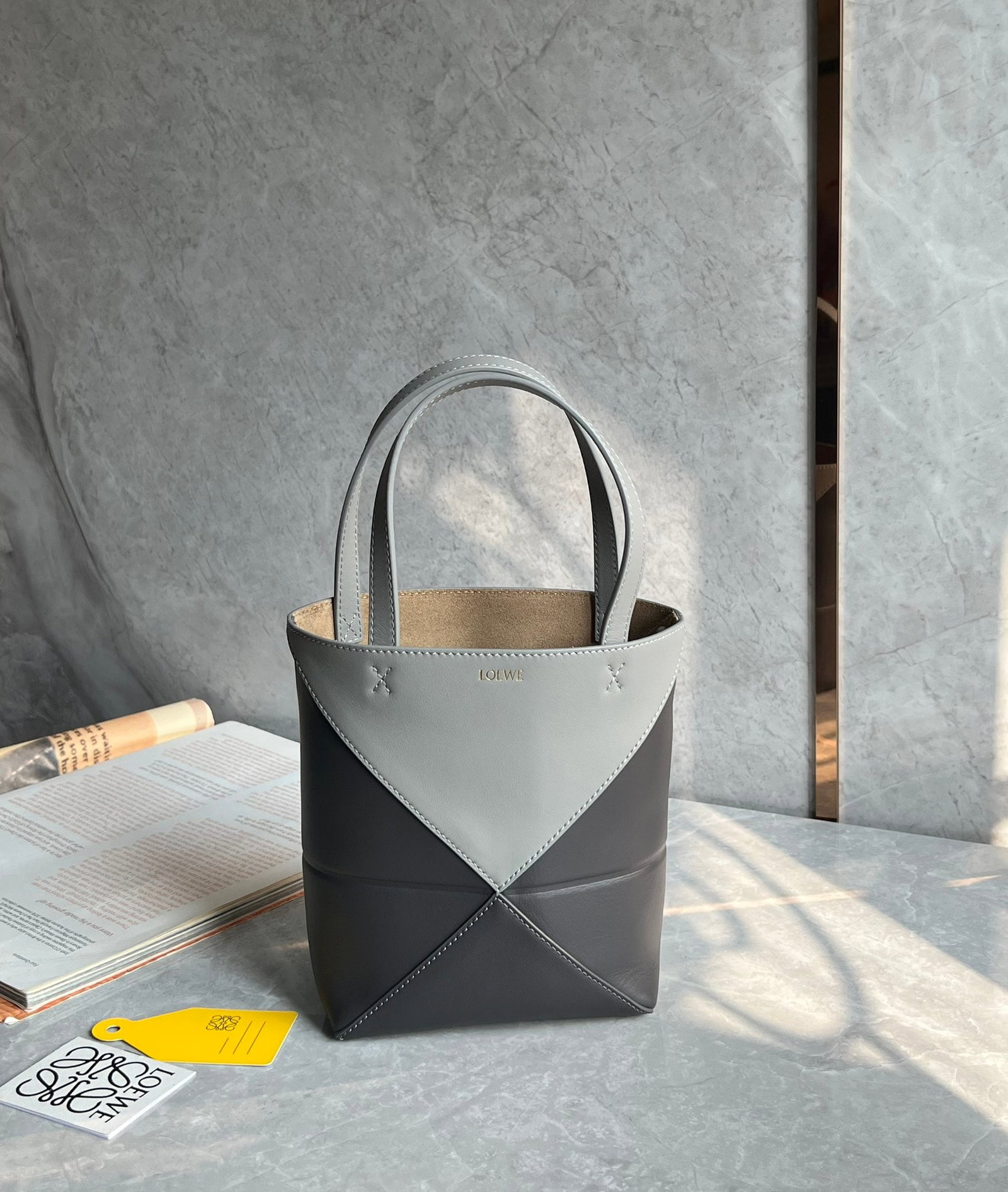 LOEWE: The LOEWE Puzzle Fold Tote bag is crafted entirely from Nappa calfskin. Inspired by origami, the Puzzle Fold Tote boasts clean lines and an understated elegance. It's incredibly soft and spacious, wit