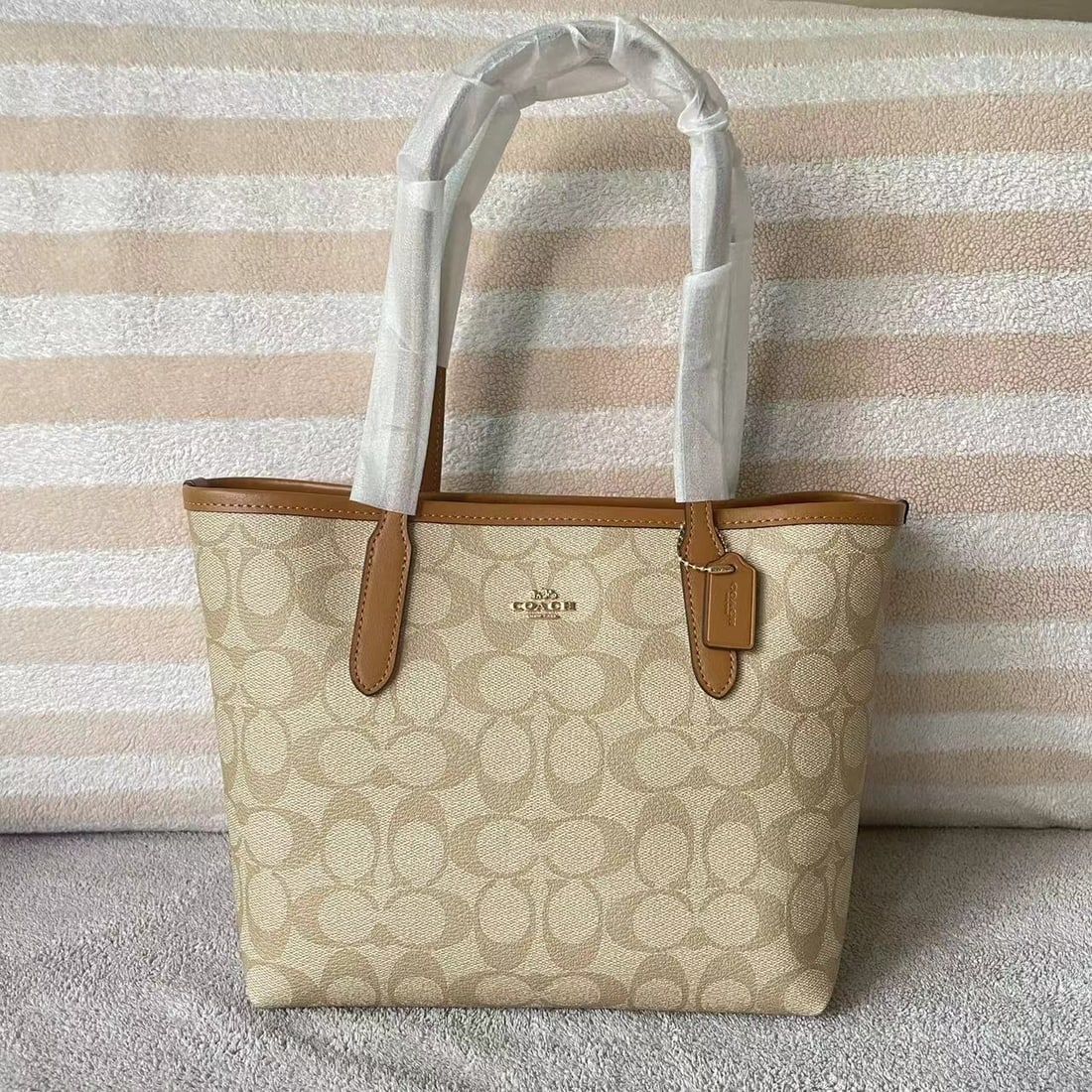 COACH: This milk tea-colored City Small tote features a double-sided bonding process to prevent creases. The interior is lined with faux leather and a monogram pattern. It's stylish, durable, and has a gener