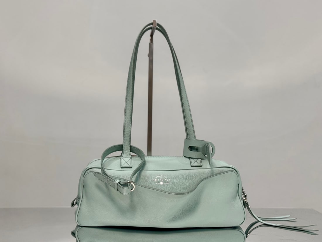 Balenciaga Carrie Bowling: The Balenciaga Carrie Bowling bag boasts a unique, curved shape with lines as fluid as musical notes, making it instantly recognizable as a Balenciaga. Its distinctive charm is undeniable; the double