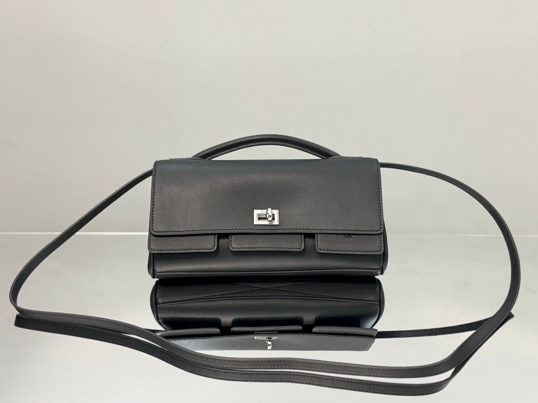 Balenciaga Bel Air Clutch: The Balenciaga Bel Air Clutch, a grey bag with silver hardware, comes with a detachable long shoulder strap. It can be carried by hand for an elegant look or worn over the shoulder for a casual charm,