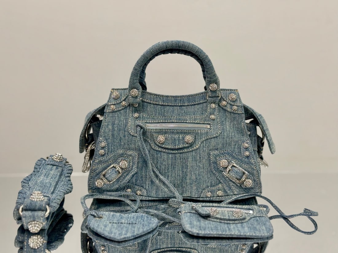 Balenciaga neo cagole motorcycle bag: The Balenciaga neo cagole motorcycle bag, with its denim and rhinestone embellishments, is exceptionally large; it can easily fit an umbrella or water bottle. The bag's intricate craftsmanship results