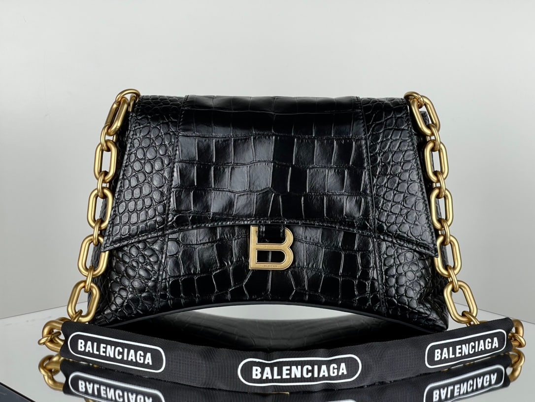 Balenciaga shoulder bag: The Balenciaga Downtown chain shoulder bag in black and gold with crocodile pattern features the same sharp angles and contours as the classic Hourglass design. The hardware and bicycle lock-like chai