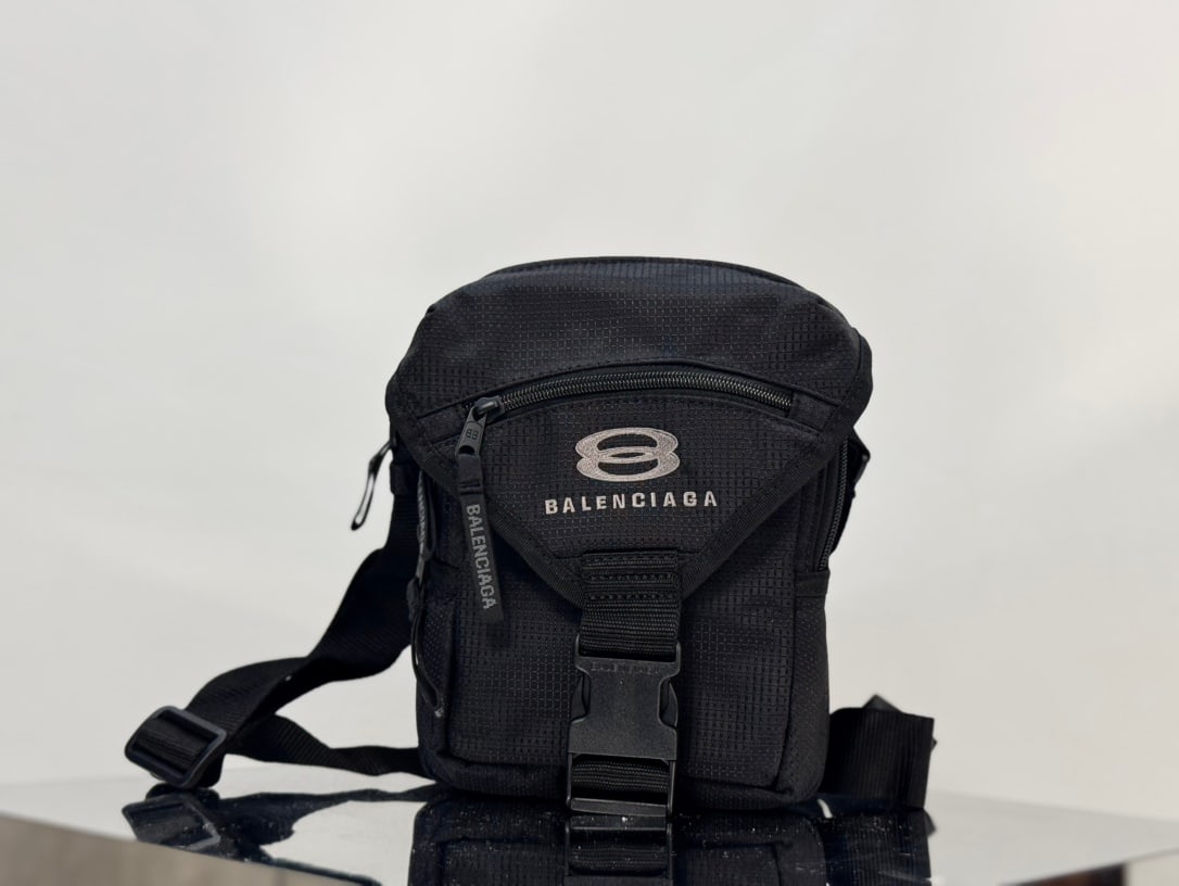 Balenciaga Unity: The Balenciaga Unity nylon crossbody bag features a Unity sports icon print on the front, matte black metal hardware, a flap closure, an adjustable shoulder strap, and multiple zippered pockets for ad