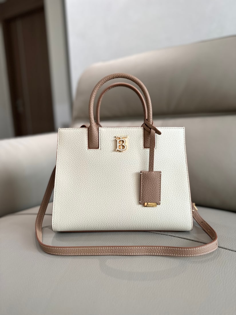Burberry: This structured Burberry tote bag is crafted from Italian-tanned grained leather and features a striking Thomas Burberry logo with a glossy finish. The sophisticated design includes multiple pockets a