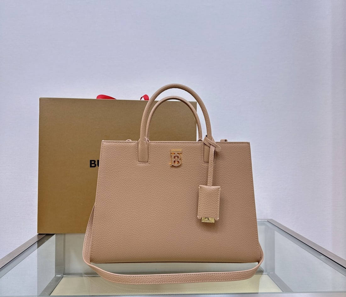 Burberry: This structured Burberry tote bag is crafted from Italian-tanned grained leather and features a striking, glossy Thomas Burberry logo. The sophisticated design includes multiple pockets and a leather-