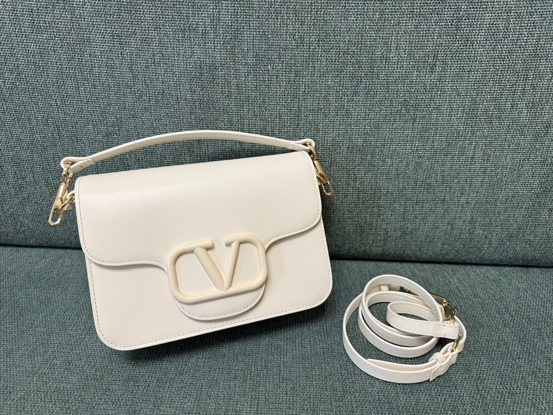 VALENTINO GARAVANI LOC0: The VALENTINO GARAVANI LOC0 valentino calfskin handbag features tonal enamel VLOGO SIGNATURE details, a detachable handle and sliding chain for versatile carrying options including hand, elbow, crossb