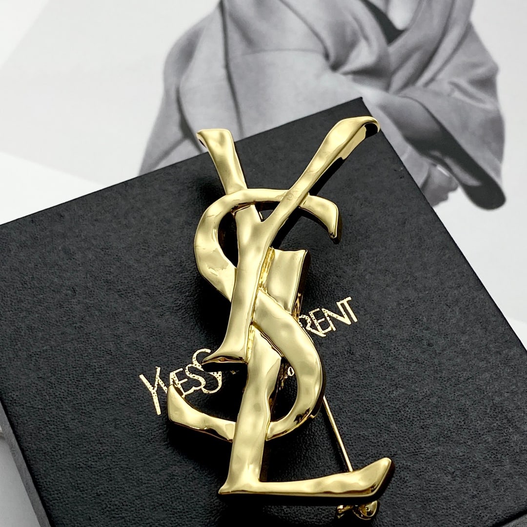 Saint Laurant Logo Brooch: The Saint Laurant logo brooch features an uneven lava-like texture and a smooth finish, a simple yet sophisticated design, and a large, impactful logo that makes a strong statement when worn,