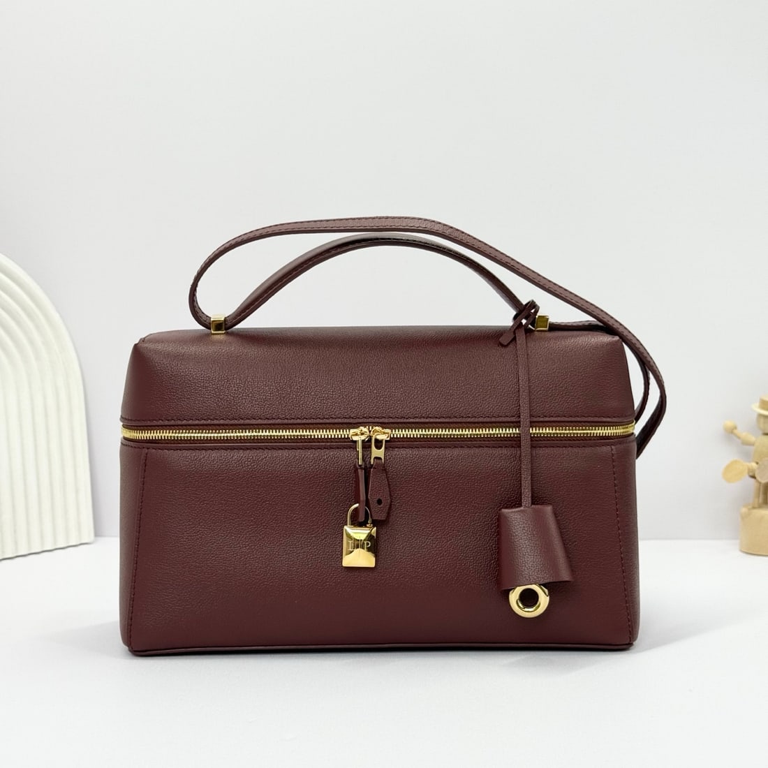 Loro Piana Extra Bag 27 Handbag: The Loro Piana Extra Bag 27, in a smoky caramel color, is crafted from calfskin with a distinctive texture. It features meticulously crafted details and stitching, a new three-dimensional charm, and a