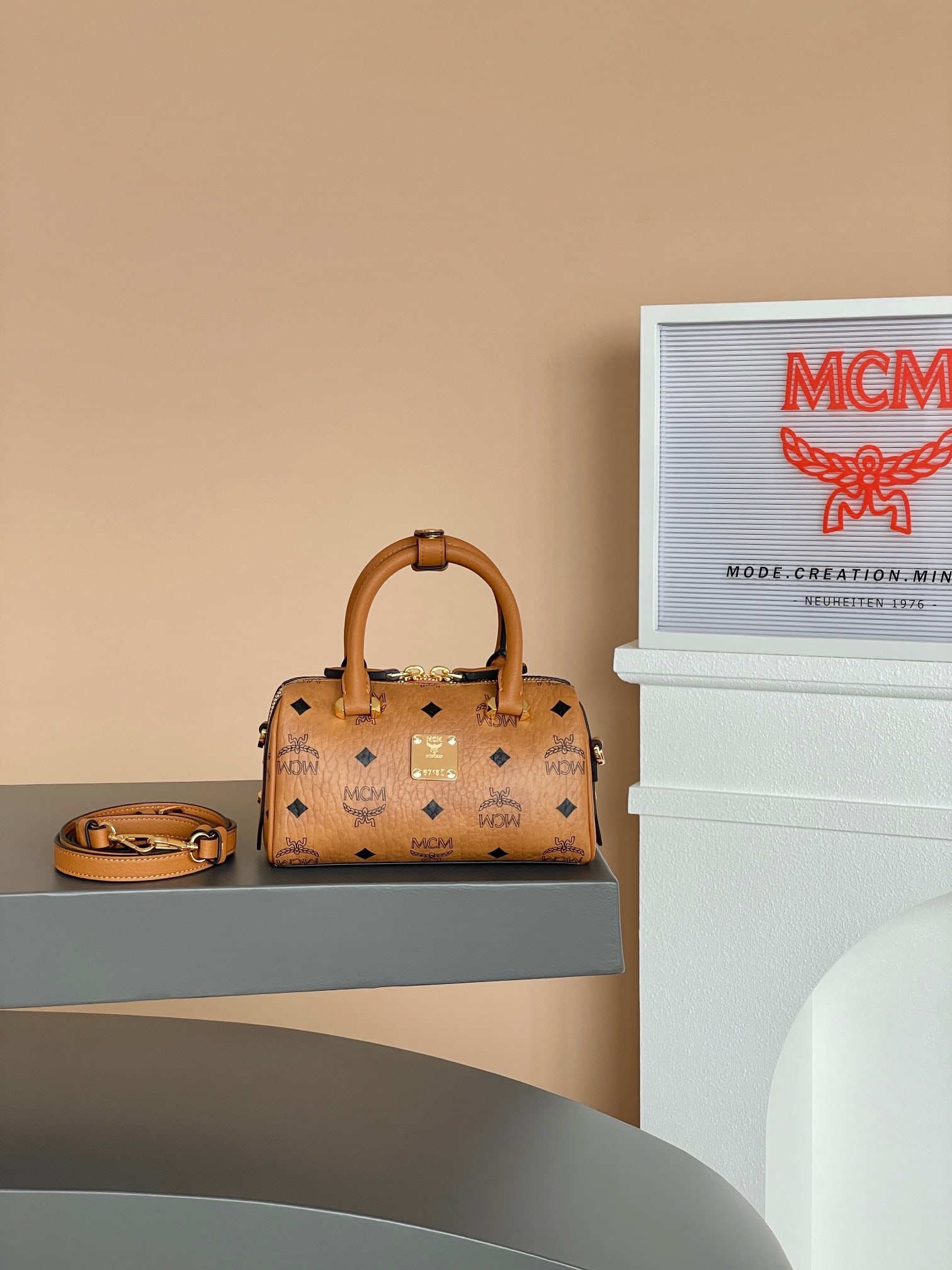 MCM AREN ESSENTIAL MINI Boston Pillow Bag: MCM AREN ESSENTIAL MINI Boston Pillow Bag in Classic Cognac Color. This mini Boston bag offers a fresh interpretation of classic style, crafted from classic Visetos material, paying homage to MCM's