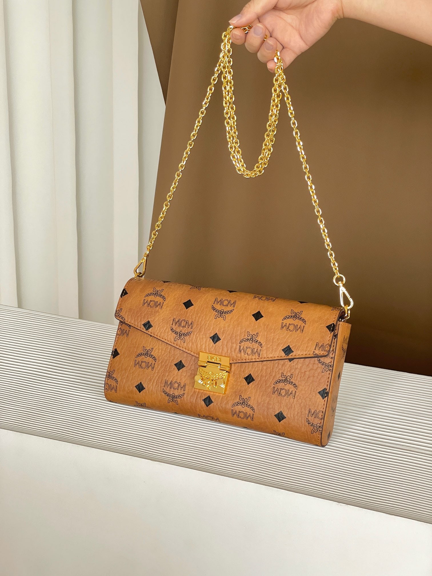 MCM TARCY VISETOS Medium Chain-Wrapped Envelope Bag: MCM TARCY VISETOS Medium Chain Envelope Bag with All-Over Monogram Print. This exceptional Tracy crossbody bag is crafted from Italian Visetos and Nappa leather. This classic tote bag features the