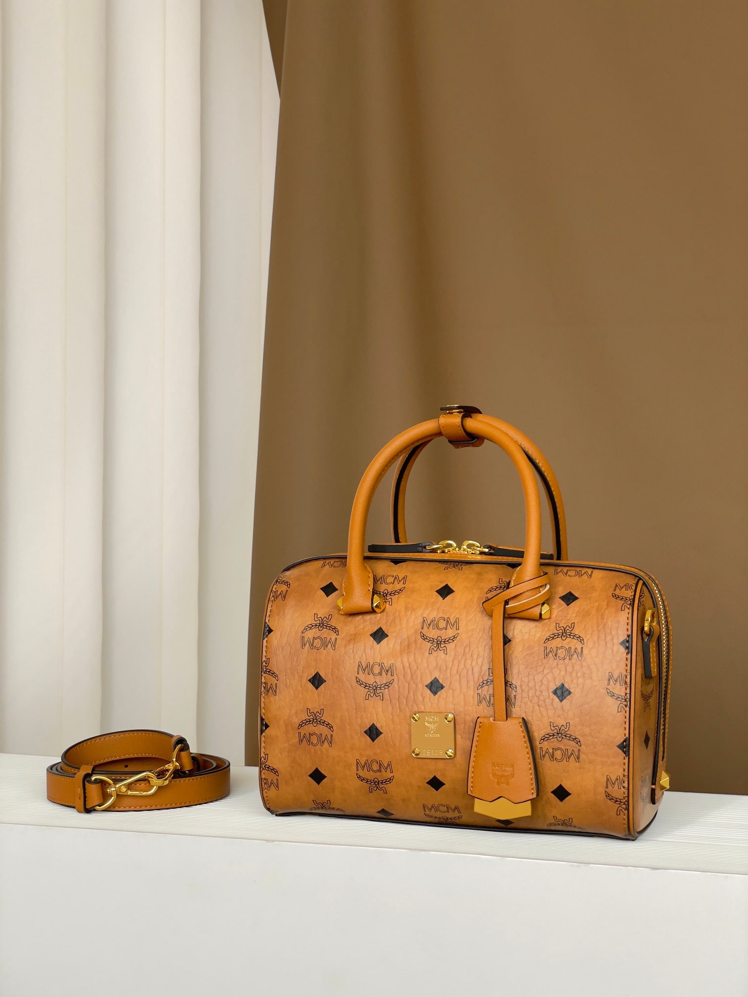 MCM AREN VISETOS SMALL Small Boston Bag: The MCM Aren Vistatus Small Boston Bag in Classic Cognac color offers a fresh interpretation of the classic design, paying homage to MCM's travel-centric philosophy. Its shape evokes a weekend