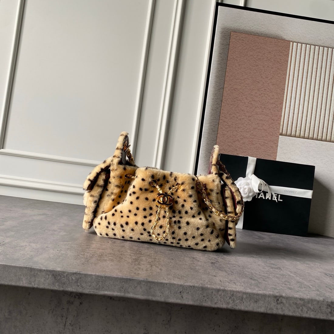 CHANEL: CHANEL Metiers d'Art collection features a plush fabric with a spotted leopard print pattern, a lambskin lining, a double C twist closure, a vintage-style distressed gold chain, a drawstring closure, 