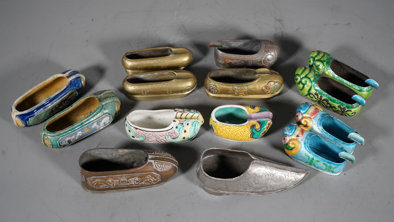 Group of 14 Antique Chinese Slipper Shoe Ashtrays: Group of 14 Antique Chinese Slipper Shoe-Shaped Ashtrays. Multi glazed ceramic, Brass and Enamel cloisonne. Measure approx. 3"L to 4"1/2. ( Stand Not Included)