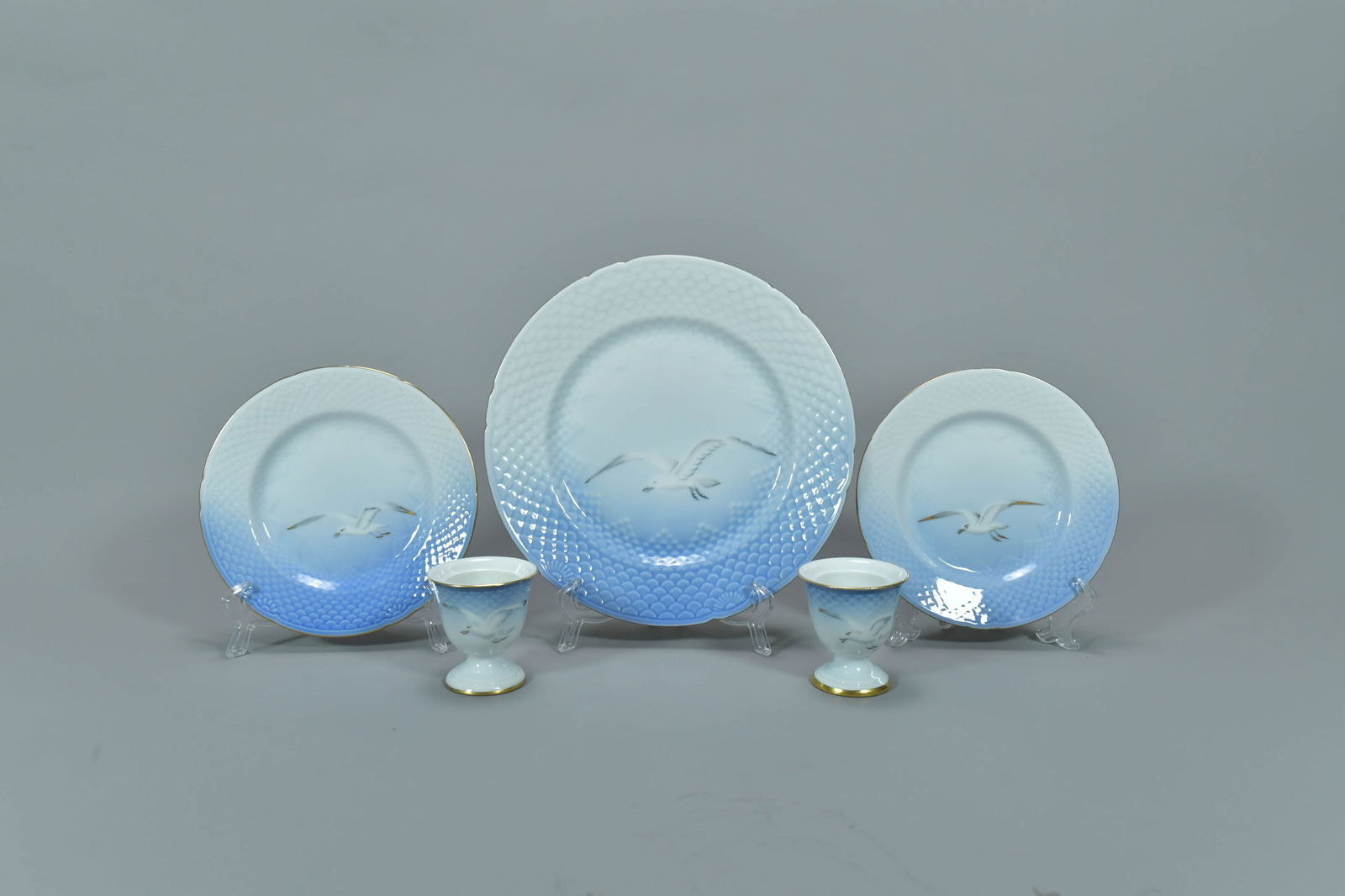 Group of 5 Vintage Danish Bing & Grondahl (B&G) Porcelain Seagull Plates & Egg Cups: Group of 5 Vintage Danish Bing & Grondahl (B&G) Porcelain Seagull Plates & Egg Cups, Hand-painted with seagulls, embossed scale patterns and gold rims. Two egg cups 2"1/4H x 2"1/4W; Two 6"1/4Dia sauce