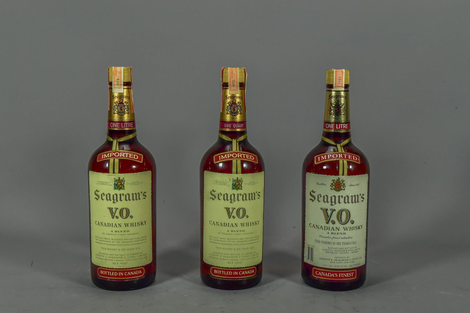 Three Bottles Seagram's V.O. Canadian Whisky, 1972, 1974 & 1983, Sealed: Three Bottles Seagram's V.O. Canadian Whisky, 1972 (one quart), 1974 (one liter) & 1983 (one liter). Fully sealed, (Stand Not Included)