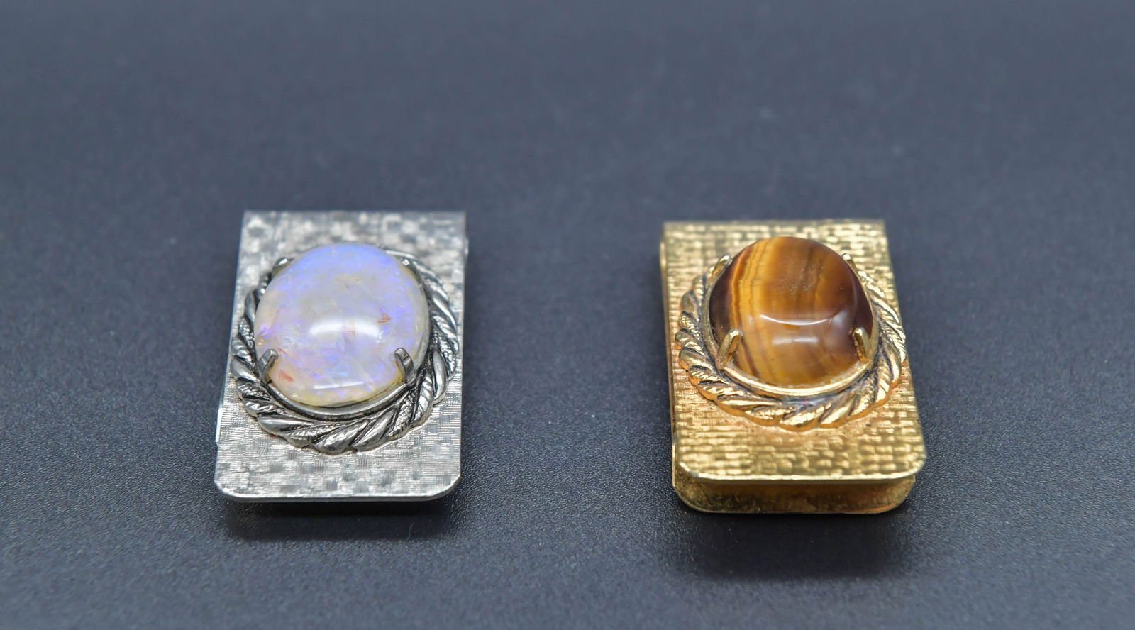 Two Fine Vintage Opal & Tiger Eye Metal Money Clips: Two Fine Vintage Opal & Tiger Eye Metal Money Clips. Silver tone metal money clip with opal stone 1"3/4"L x 1"W; Gold tone metal money clip with tiger eye stone 2"L x 1"W; In good condition, (Stand No