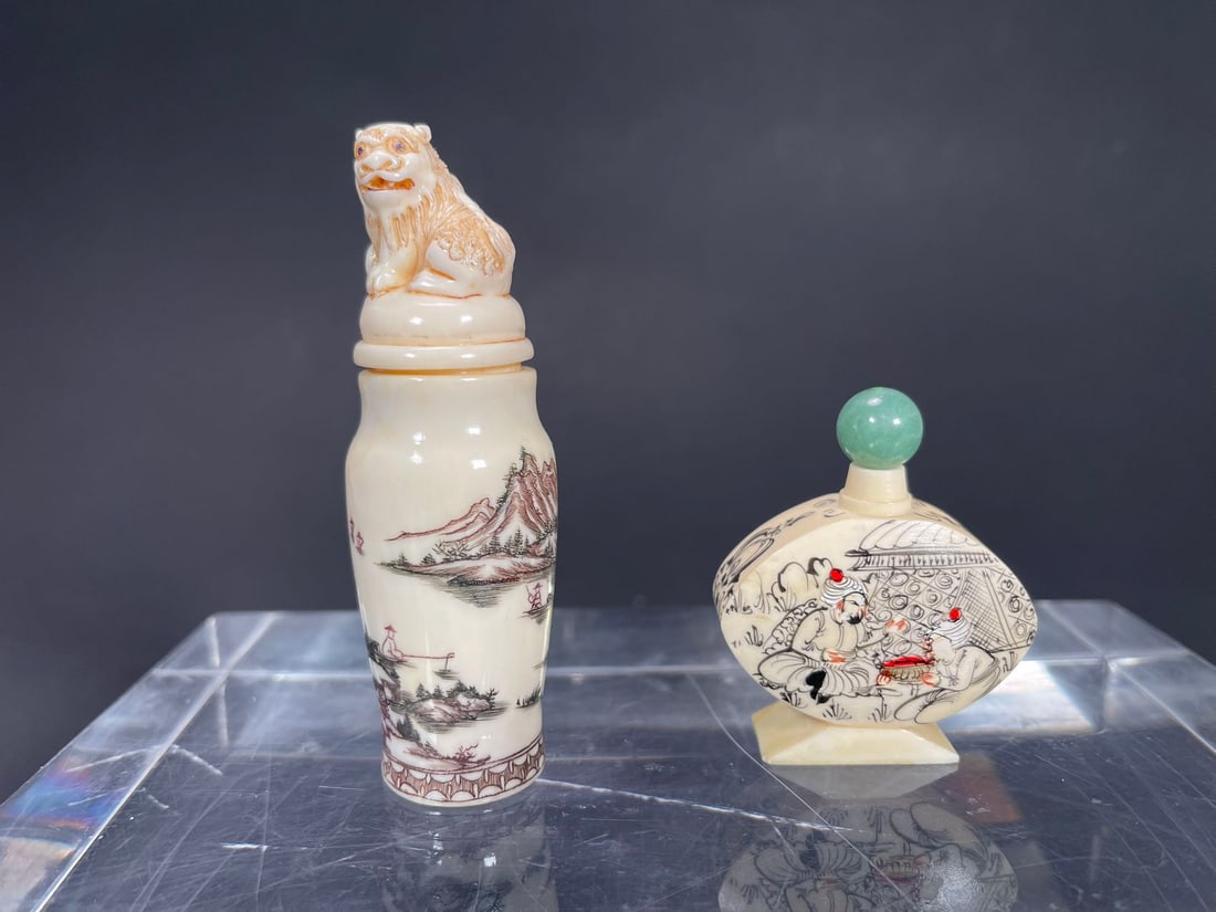 Two Vintage Bone Carved & Hand-Painted Snuff Bottles: Two Vintage Bone Carved & Hand-Painted Snuff Bottles. 1)A snuff bottle features a detailed landscape scene with mountains and fishman, the stopper is a carved lion/tiger figure, Total tall 3"1/2, Body