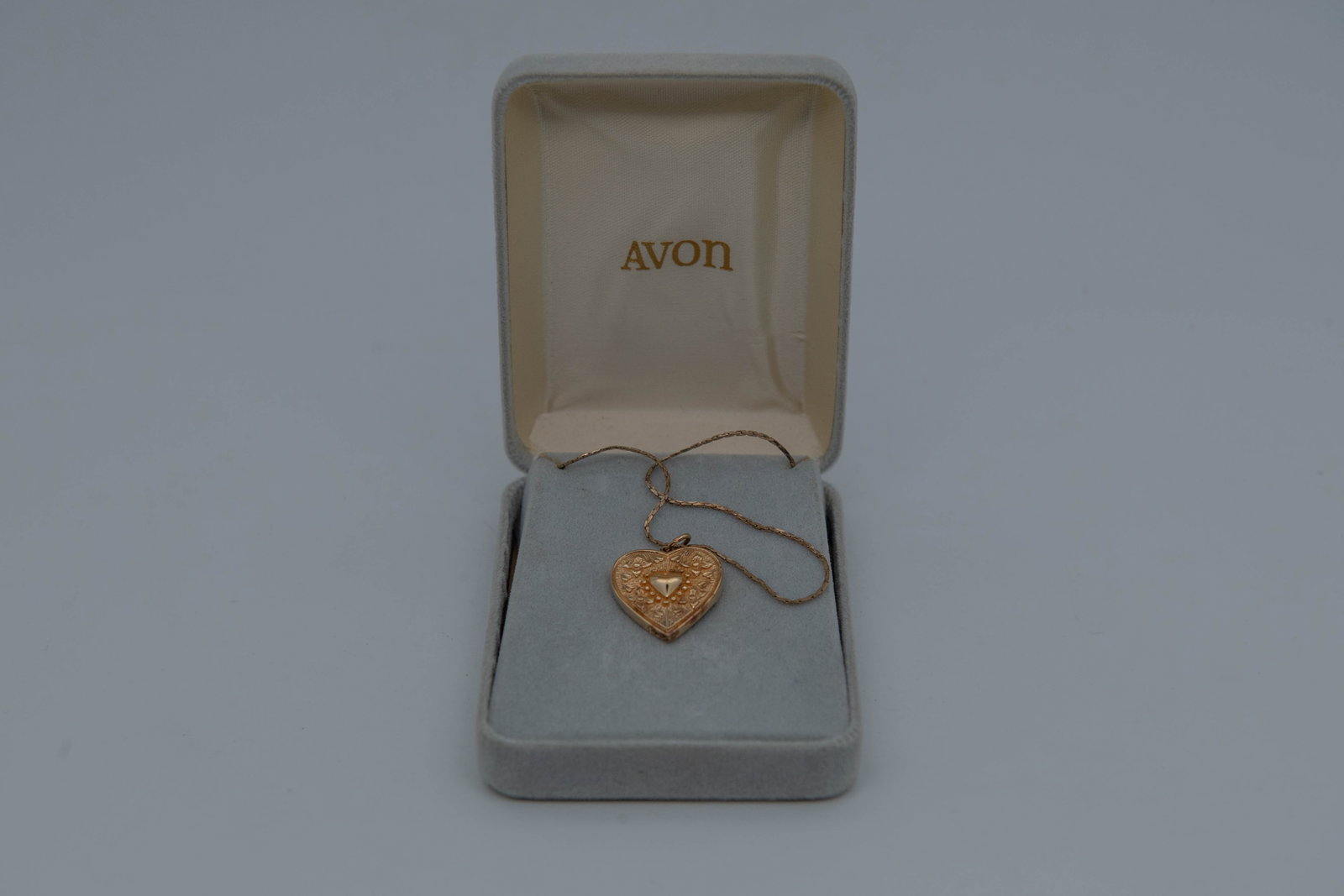 Vintage Avon "Little Orphan Annie" Heart Pendant w/14K GF Chain: Vintage Avon "Little Orphan Annie" Heart Gold Toned Pendant w/14K GF Chain. A heart gold-tone pendant filigree design with a central raised heart, 3/4" x 3/4"; 14K GF chain length 8"3/4; In good condi