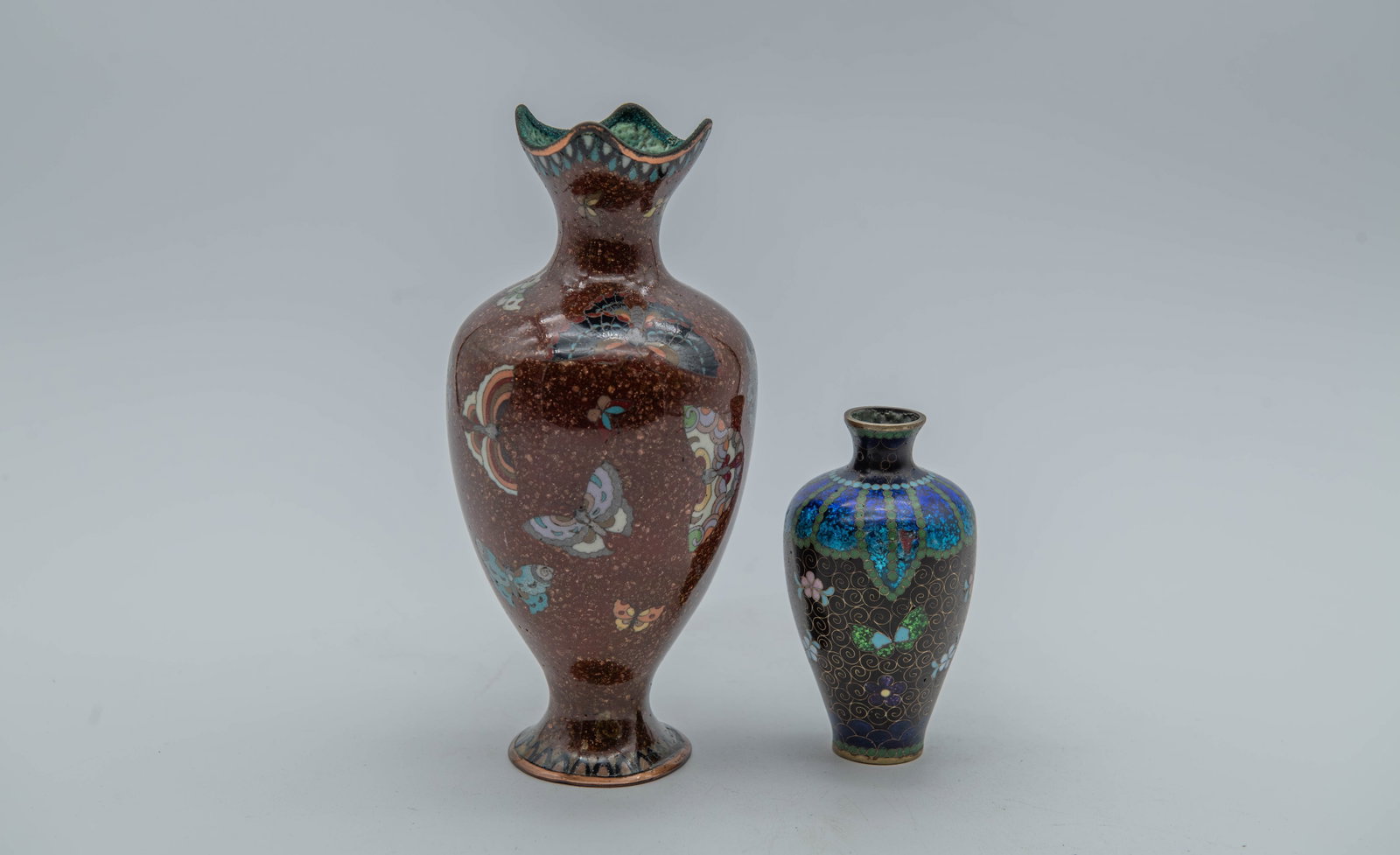 Lot of 2 Vintage Antique Japanese Cloisonne Enamel Butterfly Vases: Lot of 2 Vintage Antique Japanese Cloisonne Enamel Butterfly Vases. 1)The antique vase with a brown ground and butterfly motifs and copper base, 7"1/2H x 3"1/2W, In good overall condition; 2)The antiq
