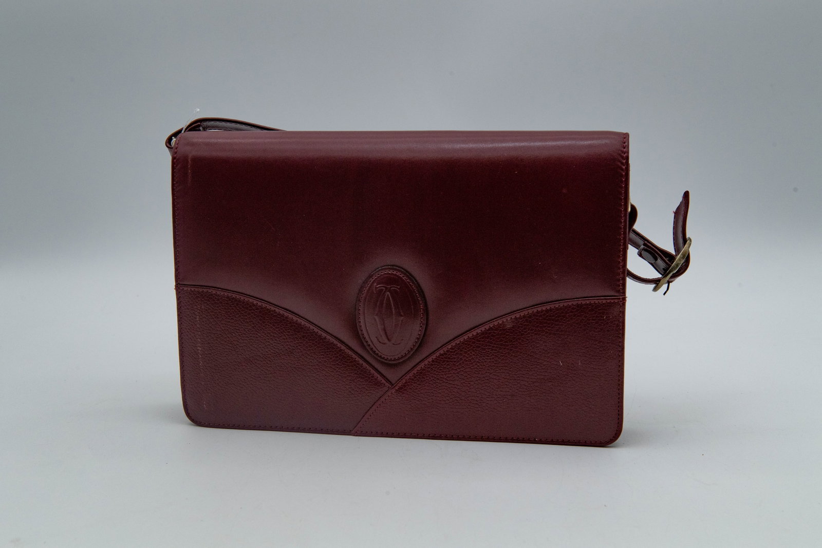 Vintage Cartier Burgundy Leather Bag: Vintage Cartier Burgundy Leather Bag. A prominent embossed Cartier Logo on the front flap. The interior is stamped with a gold-tone Cartier Paris mark, and a gold-tone plaque engraved with "Must de Ca