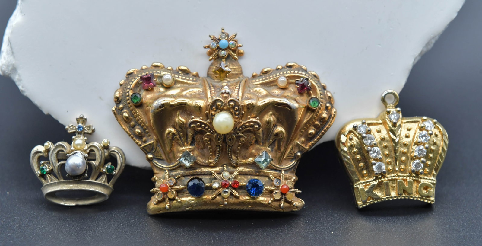 Lot of 3 Vintage Crown Brooches w/Multi Colored Rhinestones & Pearl: Lot of 3 Vintage Crown Brooches w/Multi Colored Rhinestones & Pearl. Large gold tone with multi colored rhinestone 2"1/2L x 2"1/4H; Gold tone crown pendent 1"1/4L x 1"W; Small silver tone crown pin 1"