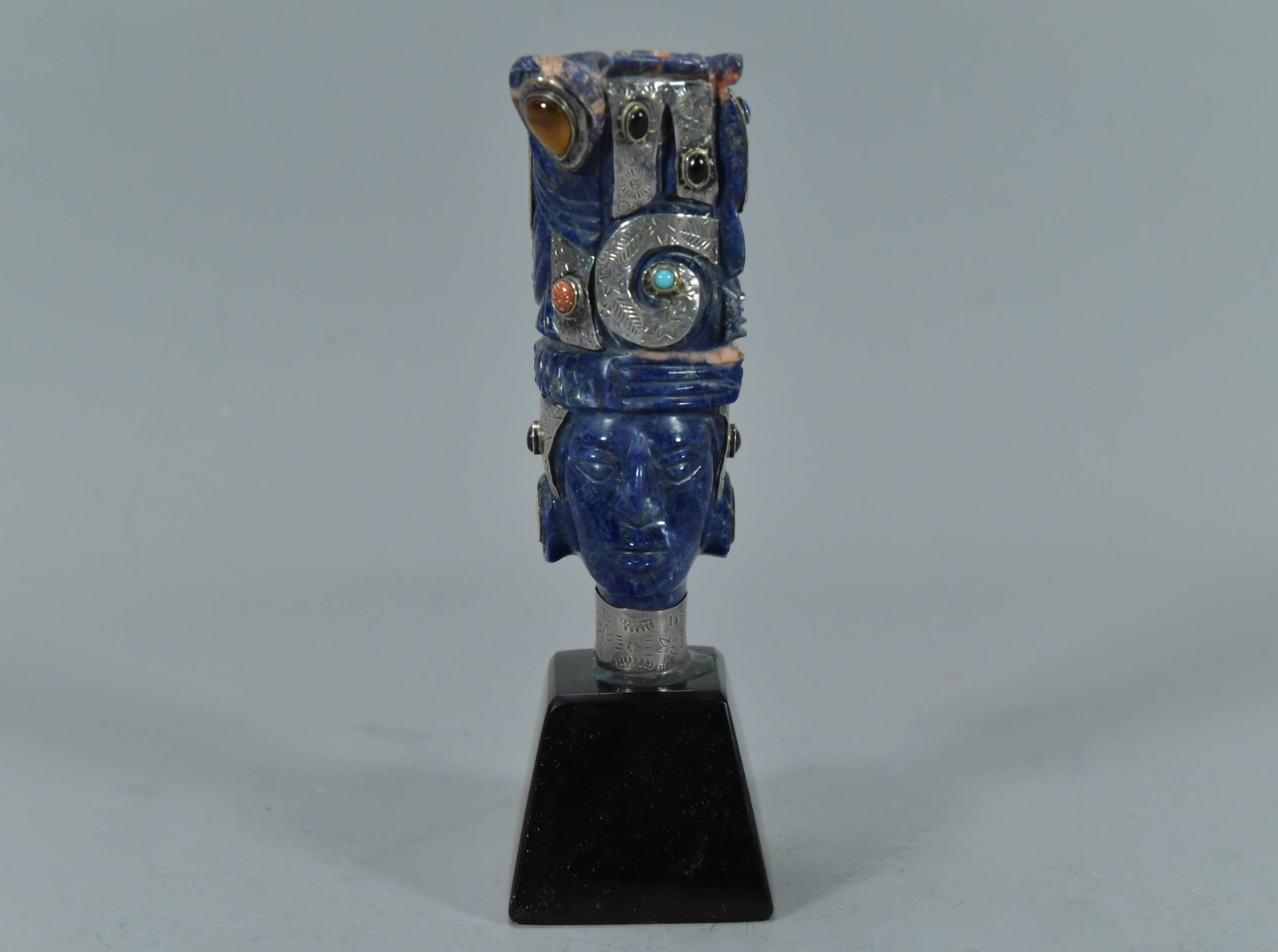 Vintage Blue Lapis Lazuli Stone Carving w/Silver Accents & Various Gemstones Inlaid on Stone Base: Vintage Blue Lapis Lazuli Stone Carving w/Silver Accents & Various Gemstones Inlaid on Stone Base, Maya God Mask Sculpture. It stands on a polished obsidian base. Total tall 7", Stand tall 1"3/4; Tota