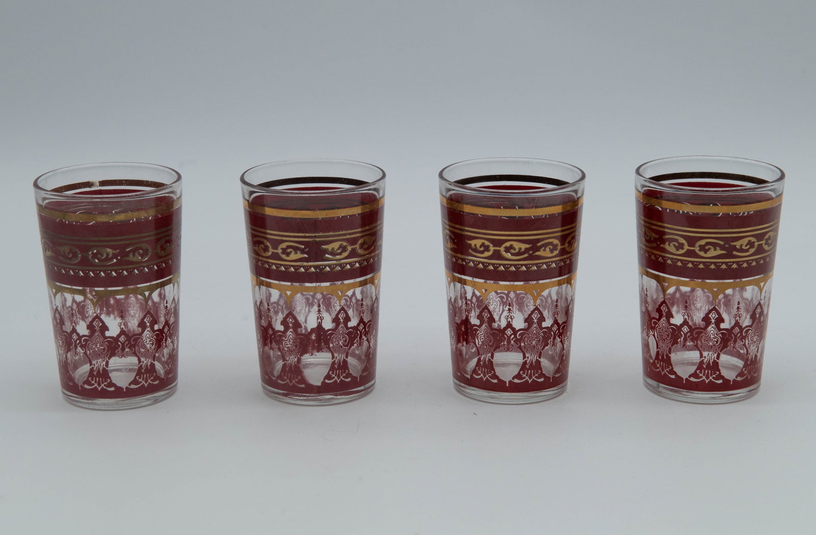 Set of 4 Red & Gold Fatima Morocco Glass/Tea Cups w/Intricate Printed Filigree Decorations: Set of 4 Red & Gold Fatima Morocco Glass/Tea Cups w/Intricate Printed Filigree Decorations. Measures 2"1/2W x 3"3/4H. Overall in good vintage condition, minor wear consistent with age and use.