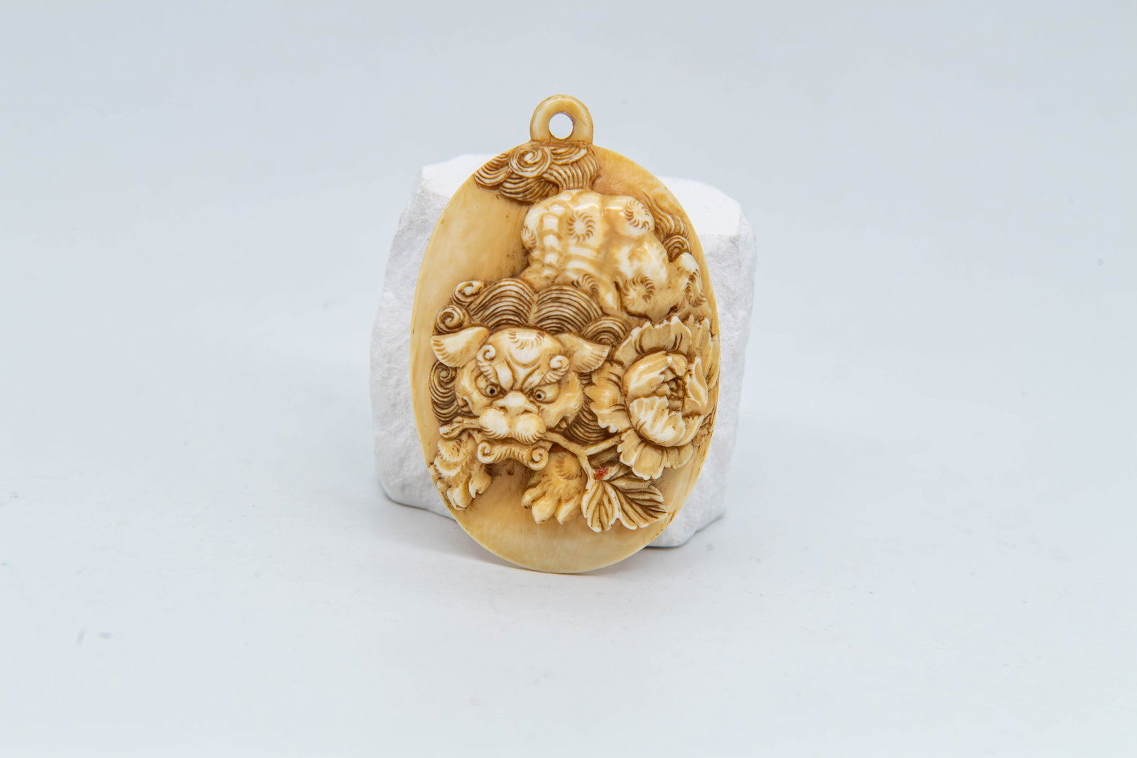 Fine Vintage Japanese/Chinese Hand-Carved Bone Foo Dog & Peony Floral Pendant: Fine Vintage Japanese/Chinese Hand-Carved Bone Foo Dog & Peony Floral Pendant. Measures 2"1/4 x 1"3/4; In good vintage condition, (Stand Not Included)