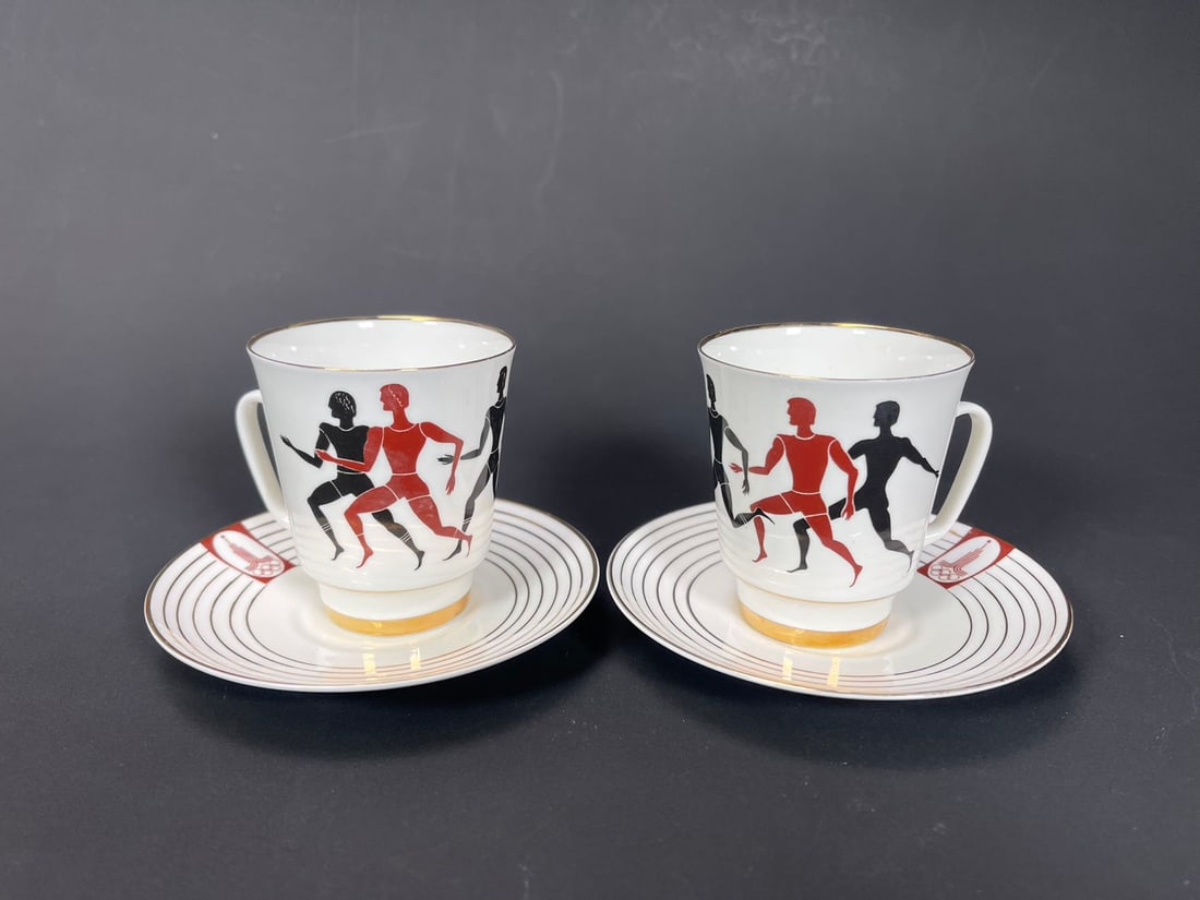 Two Sets of Rare Lomonosov Russian Porcelain 1980 Moscow Olympics Gold Trim Cups & Saucers: Two Sets of Rare Lomonosov Russian Porcelain 1980 Moscow Olympics Gold Trim Cups & Saucers. Cup 2"3/4W x 3"H, Saucer 4"3/4W; In good condition, (Stand Not Included)