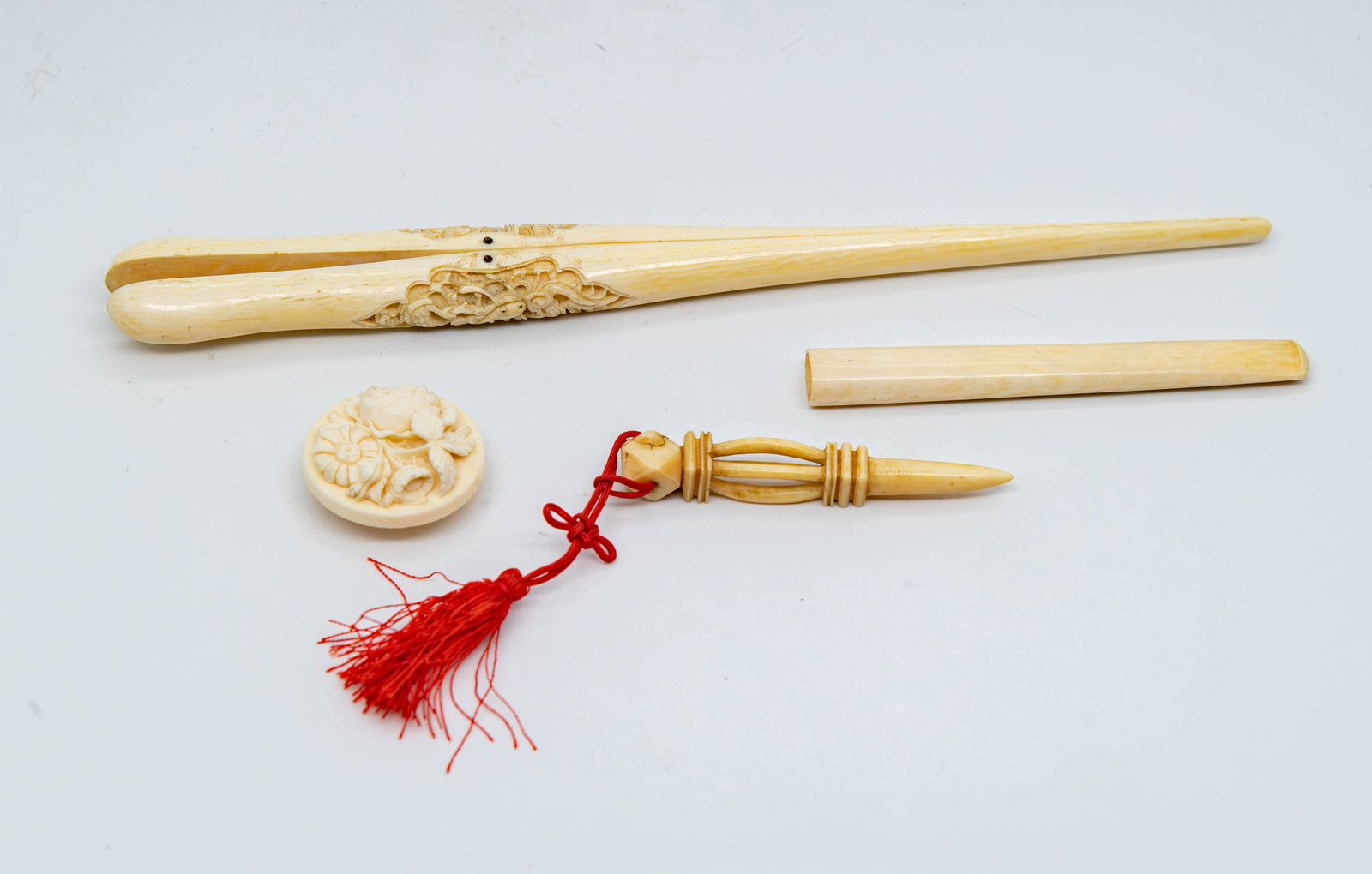 Lot of 4 Vintage Hand-Carved Bone Pieces: Lot of 4 Vintage Hand-Carved Bone Pieces. 1)Cigarette holder 4"L x 1/2"W; 2)A carved piece possibly sewing tool, 3"L; 3)A carved relief floral brooch or button, Diameter 1"1/2; 4)Antique glove stretch