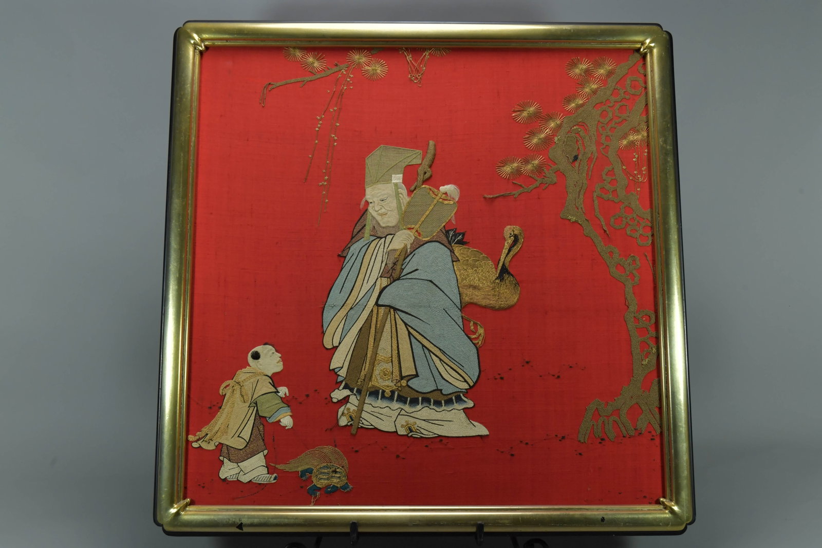Framed Vintage Chinese Silk Embroidery Panel w/Fu Xing Figure: Framed Vintage Chinese Silk Embroidery Panel w/Fu Xing Figure. The panel depicting a scene with Fu Xing - the god of happiness, a crane and child on a red background. Framed size 28" x 29", In good co