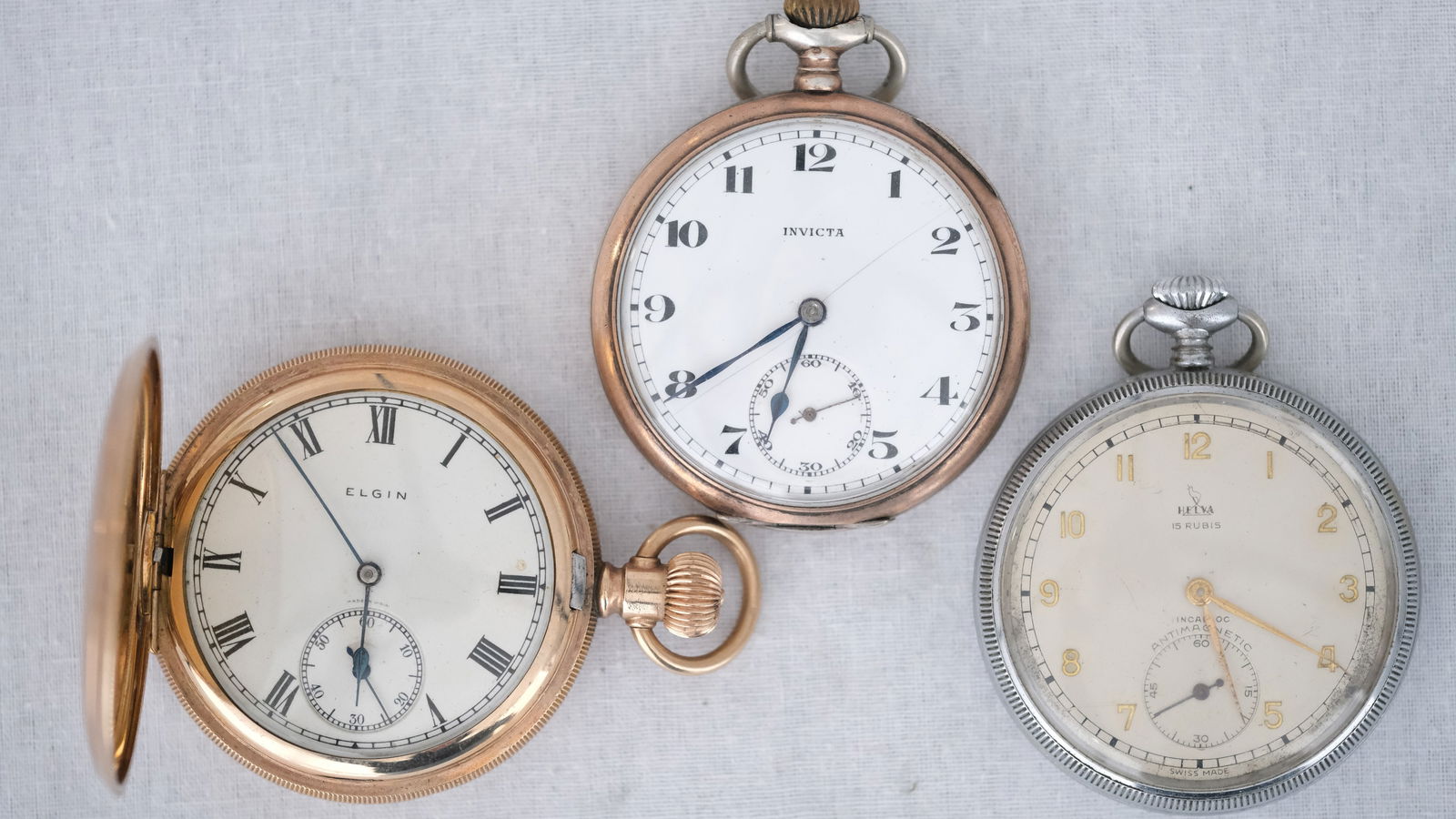A Various lot of three Antique Pocketwatches - One Silver by Invicta, One Helva and One Elgin gold: A Various lot of three Antique Pocketwatches - One Silver by Invicta, One Helva Swiss movement and One Elgin gold plated. One silver and two metal. Diam. 35 - 35 - 37 mm. Silver Hallmark and 0.800. 19