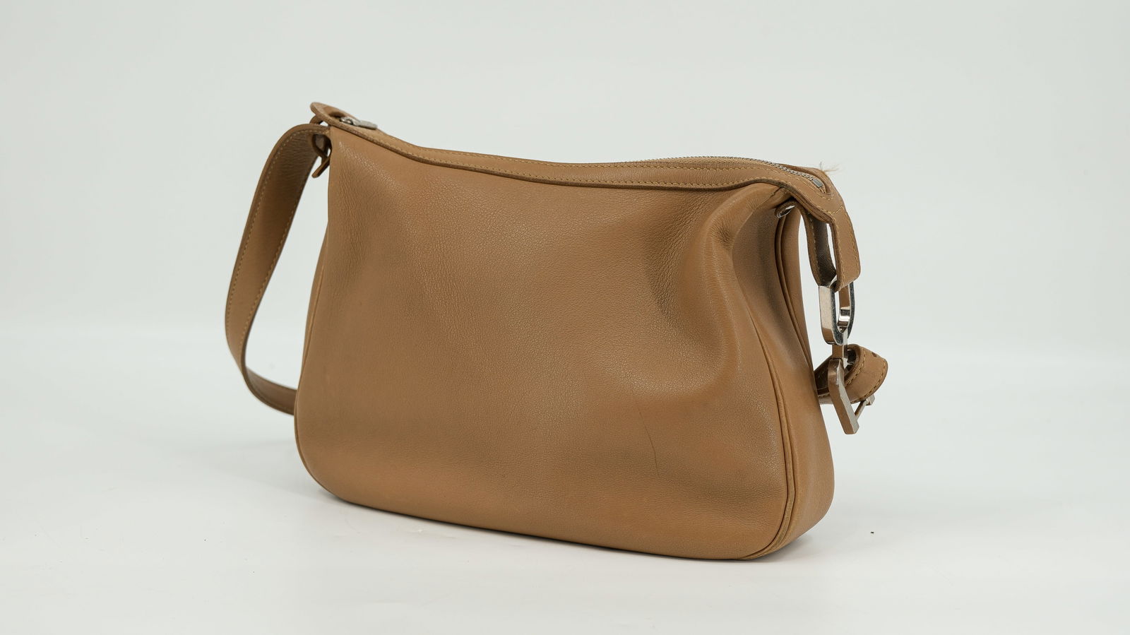 A Delvaux shoulder bag in brown leather: A Delvaux shoulder bag in brown leather and silver hardware. The strap is adjustable and has a visible double D logo. The bag closes with a zipper. The interior has one big compartment and a side pock