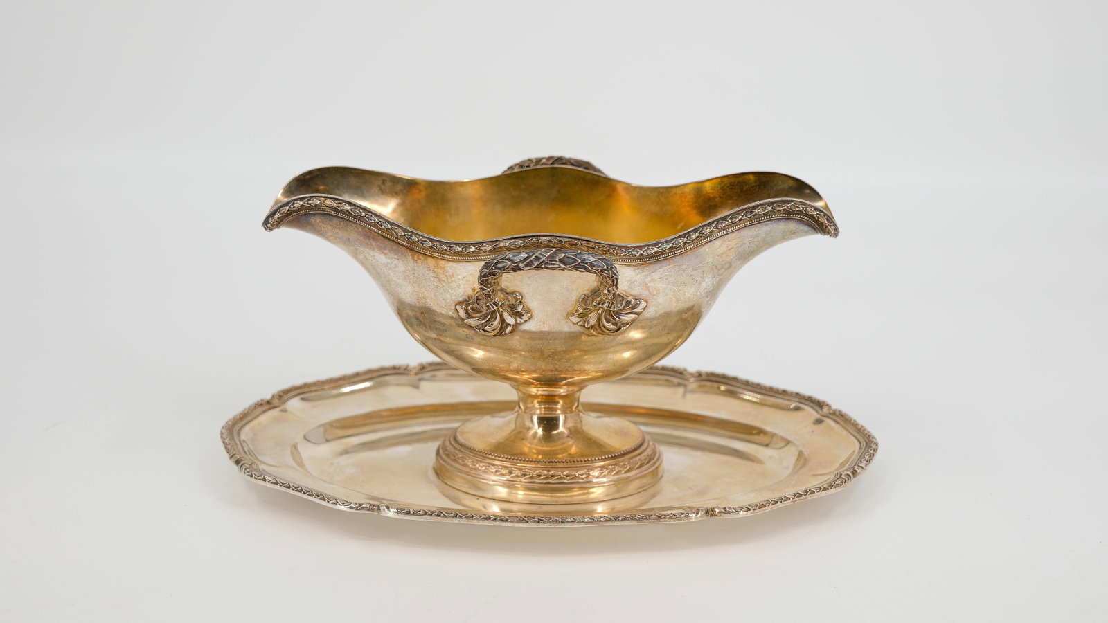 A Neoclassical style Silver Sauciere boat with handles. Hallmarks and 19th Century: A Neoclassical style Silver Sauciere boat with handles. Inside gilded vermeille. Hallmarks and 19th Century. Weight: 630,31 gr. H: 12 cm - W: 26,5 cm