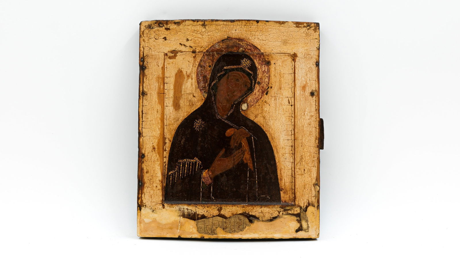 An antique Russian tempera on wood icon of the Virgin Mary in prayer with gilded halo