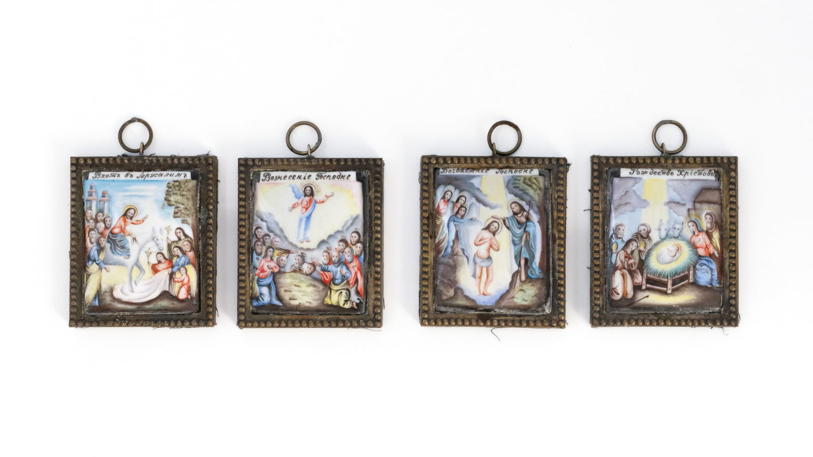 A lot of four matching antique Russian enamel and gilt brass miniatures of feast scenes: A lot of four matching antique Russian enamel and gilt brass miniatures depicting the Entry into Jerusalem, Ascension, Baptism of Christ and Nativity, each mounted in a square brass frame with beaded