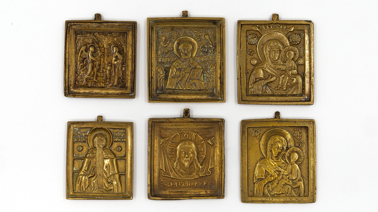 A lot of six antique Russian cast bronze square icon plaques with relief decoration: An antique Russian set of six cast bronze square icons depicting the Annunciation, Christ, the Mother of God with Child and various saints, each with detailed relief and inscriptions, all fitted with