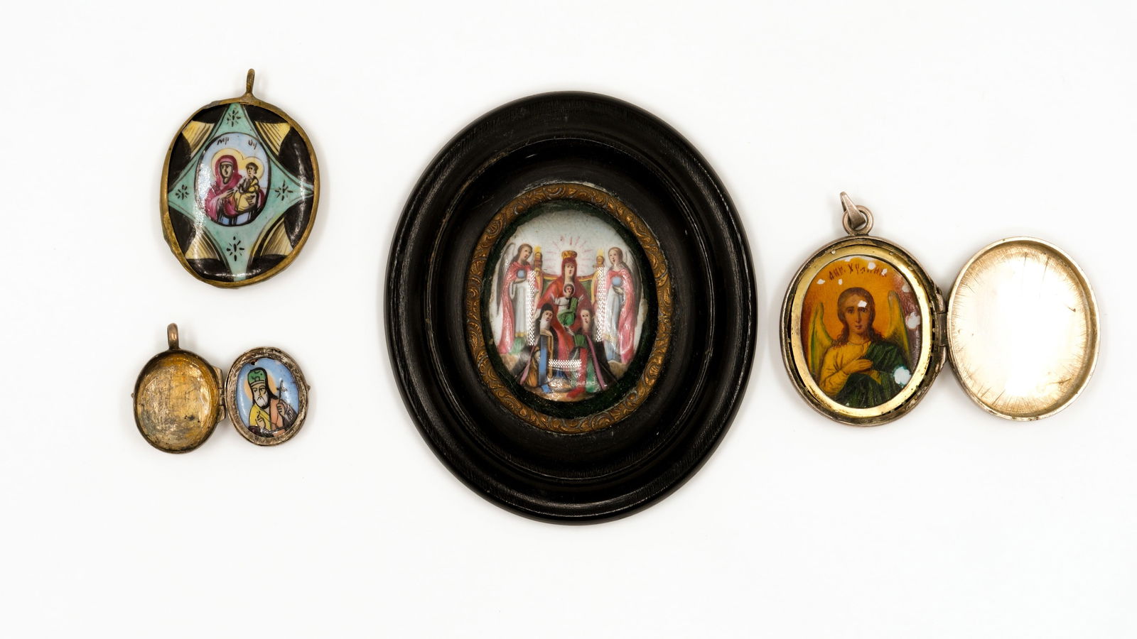 A composed lot of four antique Russian silver and enamel decorated pendants and an oval miniature: A composed lot of four antique Russian silver and enamel decorated pendants and an oval miniature framed wall plaque, depicting various saints and holy figures, including the Mother of God with Child