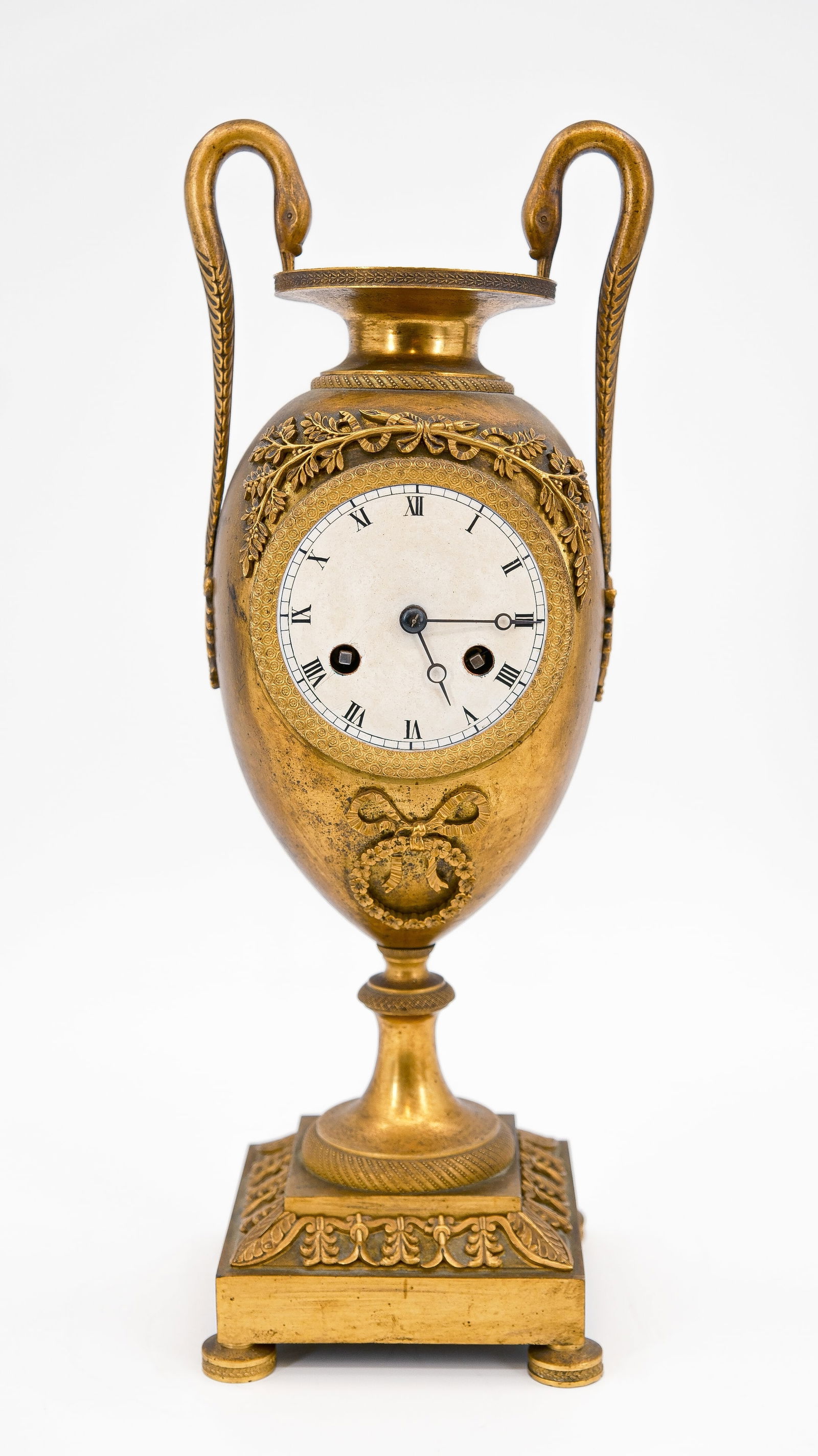 A French antique Empire style fire-gilt bronze vase clock with swan-shaped handles: A French antique Empire style fire-gilt bronze vase clock with swan-shaped handles. First half 19th century. H: 40 cm