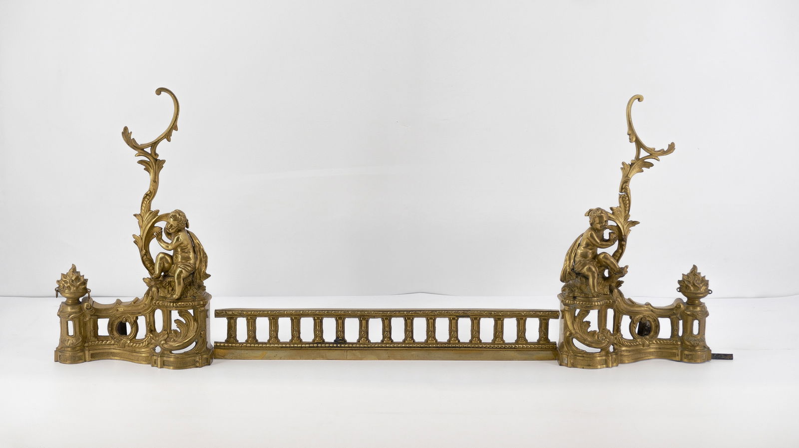 A French antique three-part gilt brass fireplace fender with two figural putti: A French antique three-part gilt brass fireplace fender with two figural putti. Circa 1900. H: 50 - W: 108 cm