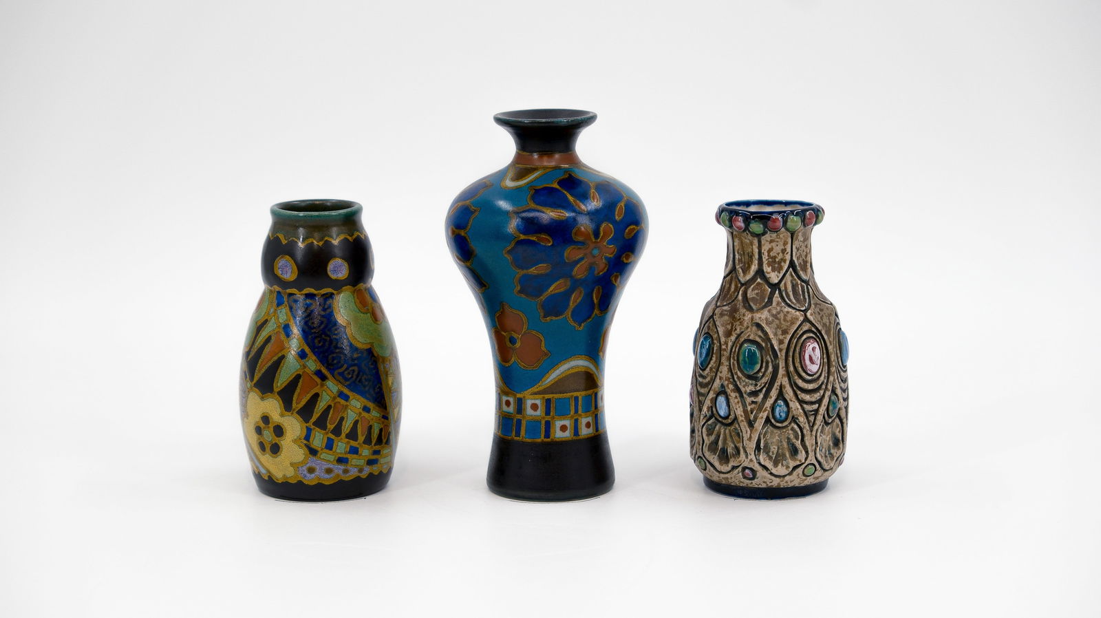 A composed lot of three small decorated ceramic vases by Gouda and Amphora: A composed lot of three small decorated ceramic vases by Gouda and Amphora. Consisting of: two Gouda vases and one Amphora marked. 20th century. H: 12 - 15,5 cm