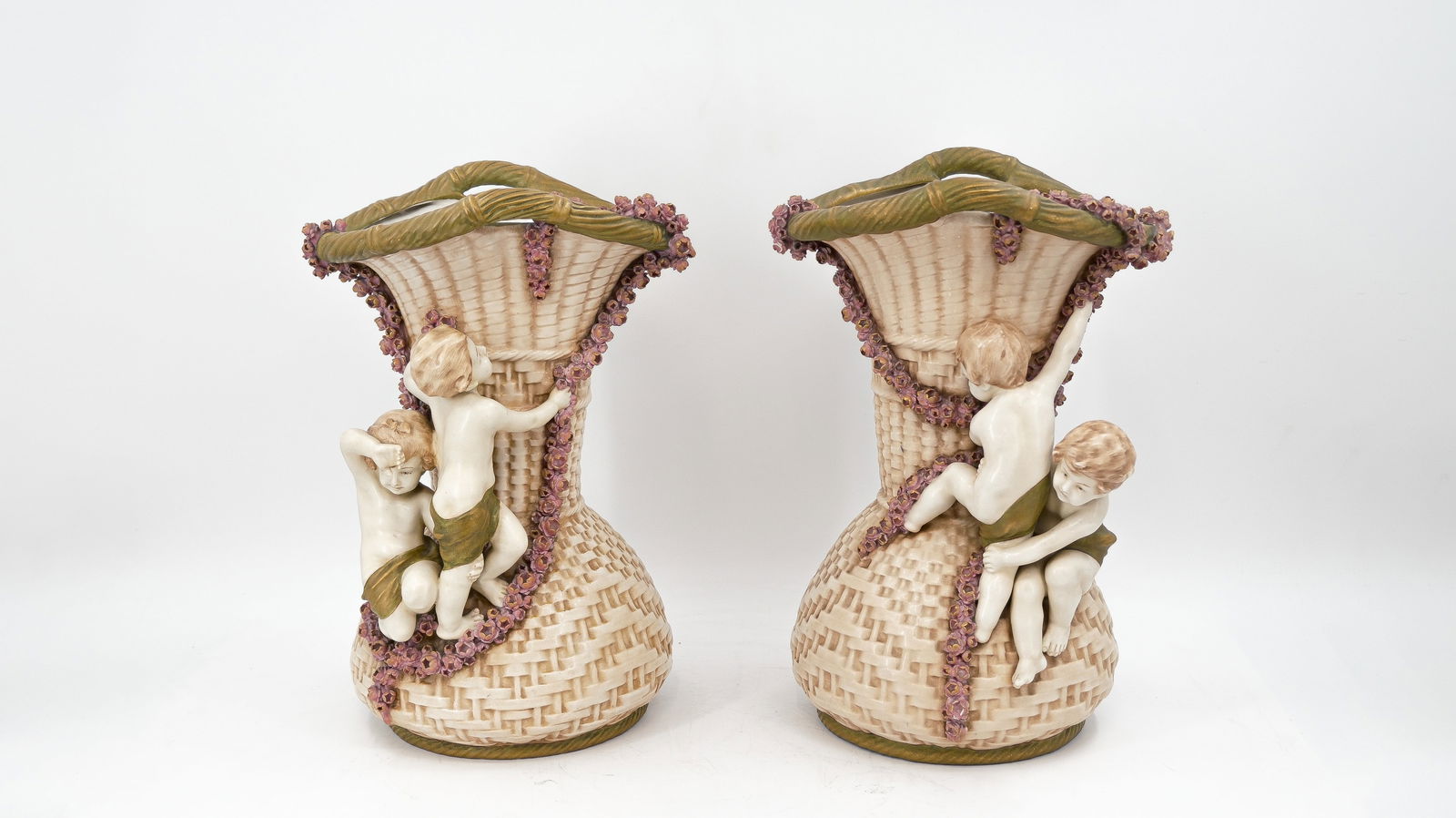 A lot of two matching Bohemian Austria Amphora ceramic basket vases with climbing amors???: A lot of two matching Bohemian Austria Amphora ceramic basket vases with climbing amors. Marked and circa 1900-1920s. H: 42,5 cm