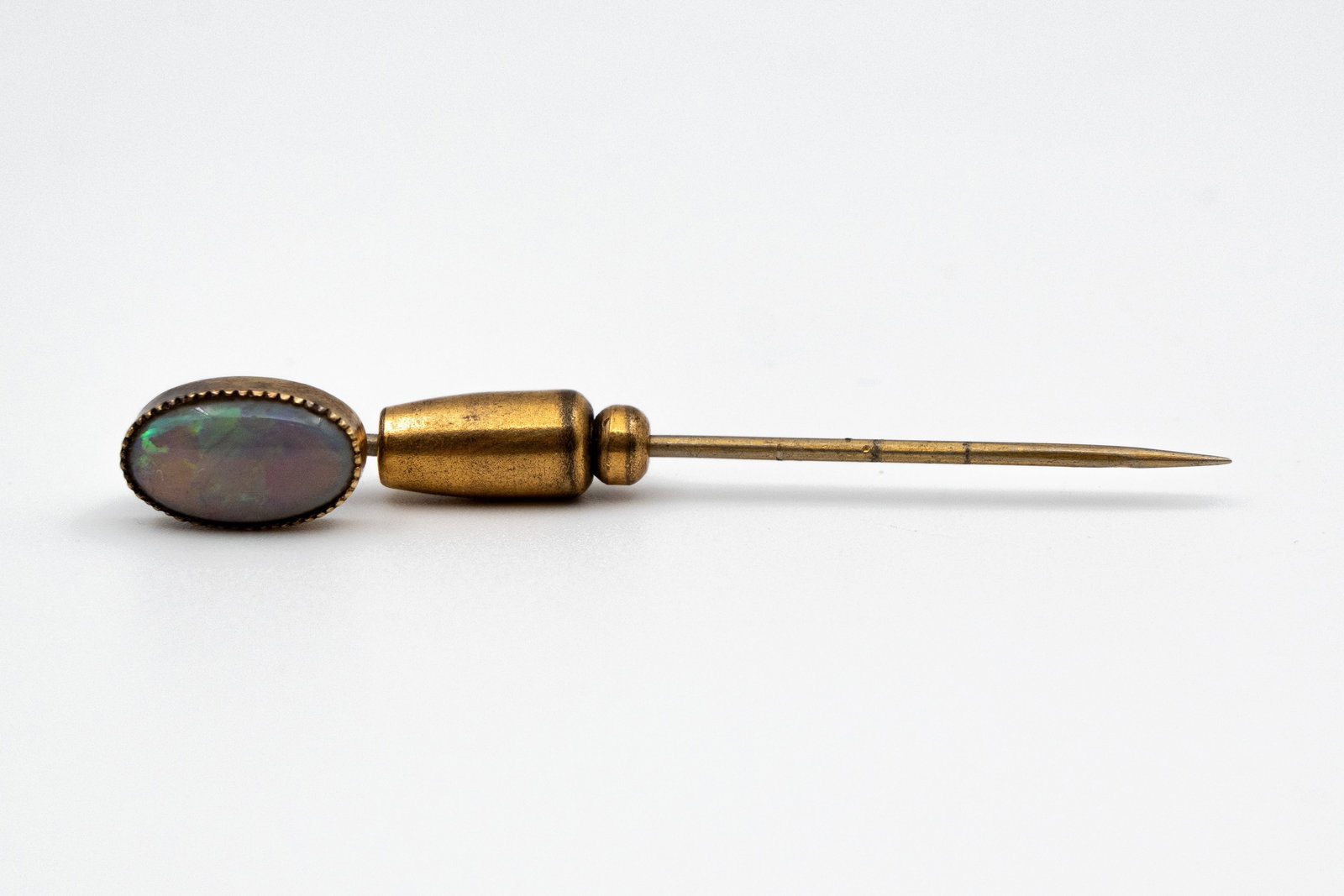 An 18 kt Gold and nickel stick pin with an oval opal-colored stone (1 of 4)