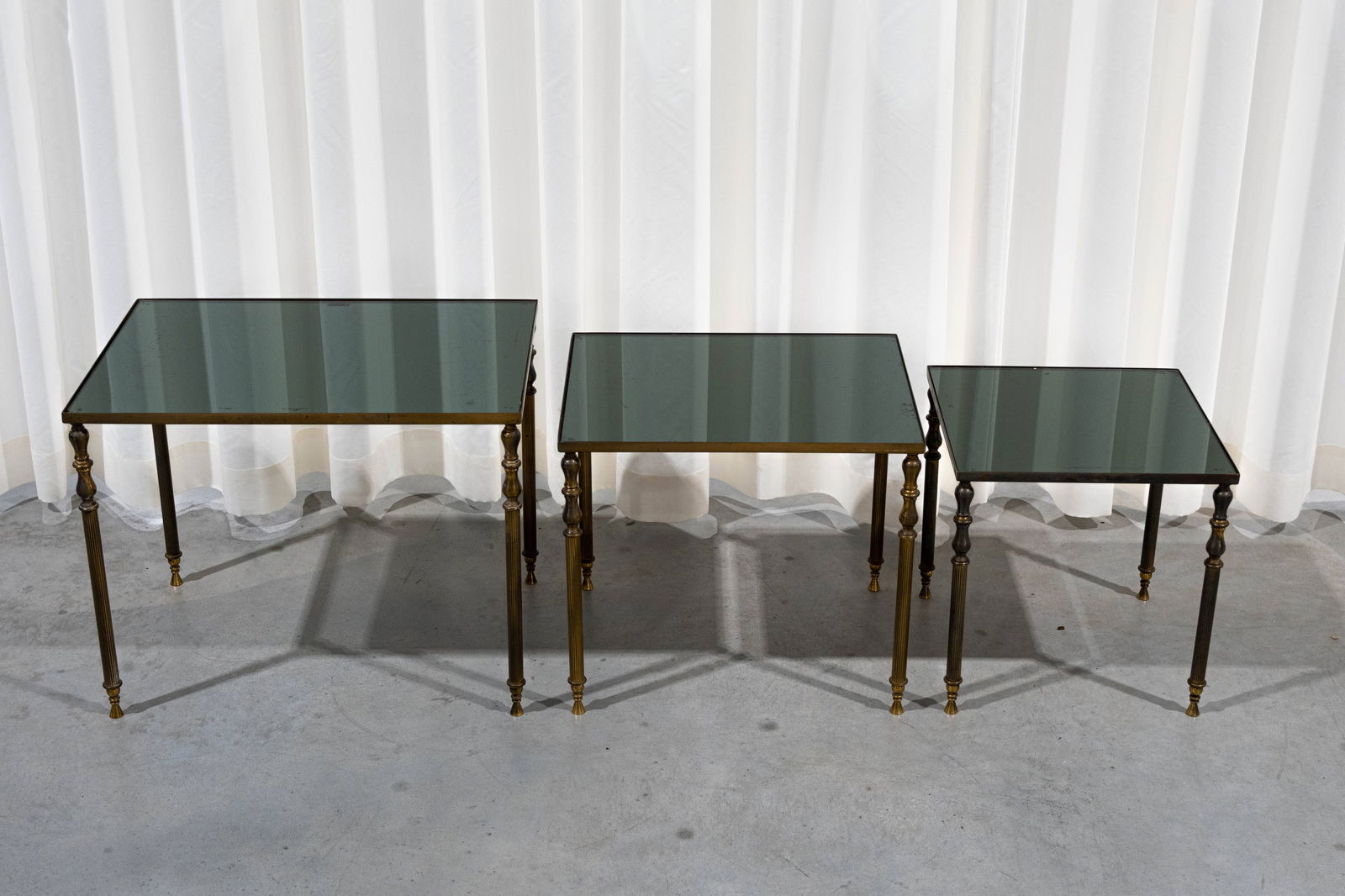 A set of vintage nesting tables in brass and fumed glass: A set of vintage nesting tables in brass and fumed glass. Circa 1950s. H: 44 - W: 55 - D: 41 cm, largest