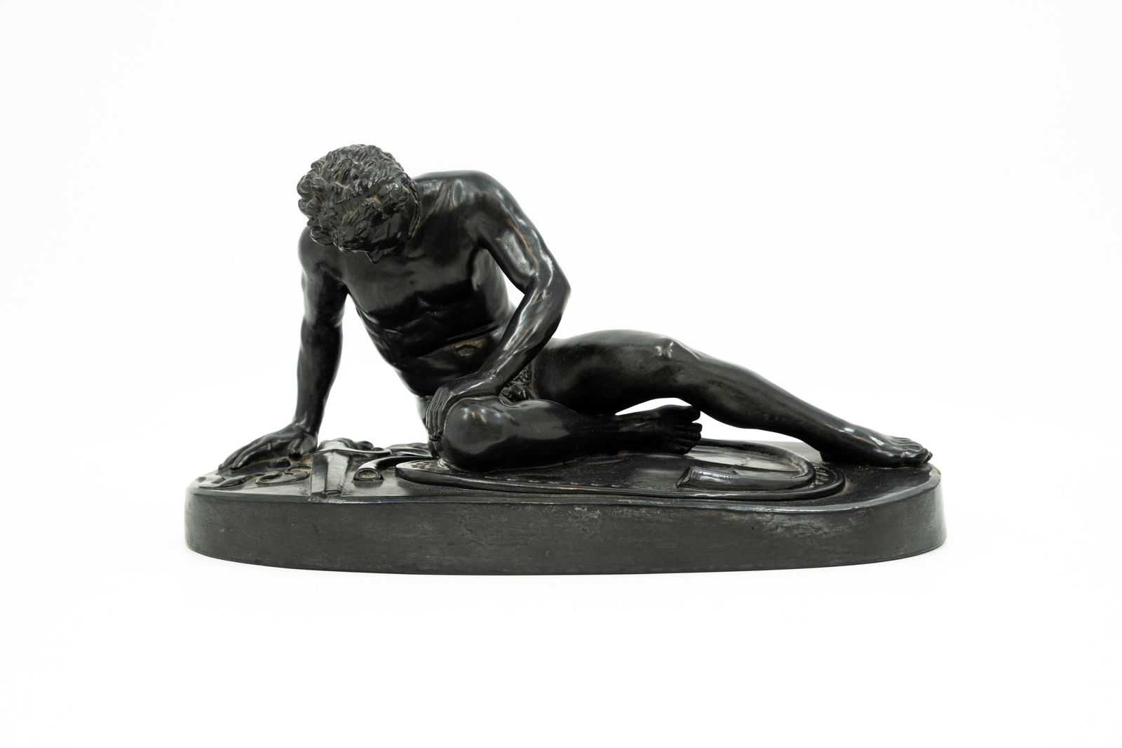 A patinated terra cotta figure depicting The Dying Gaul: A patinated terra cotta figure depicting The Dying Gaul, Grand Tour, after the antique. Marked P. Ipsen and illedgibly signed. Circa 1900. H: 19,5 - W: 38 cm