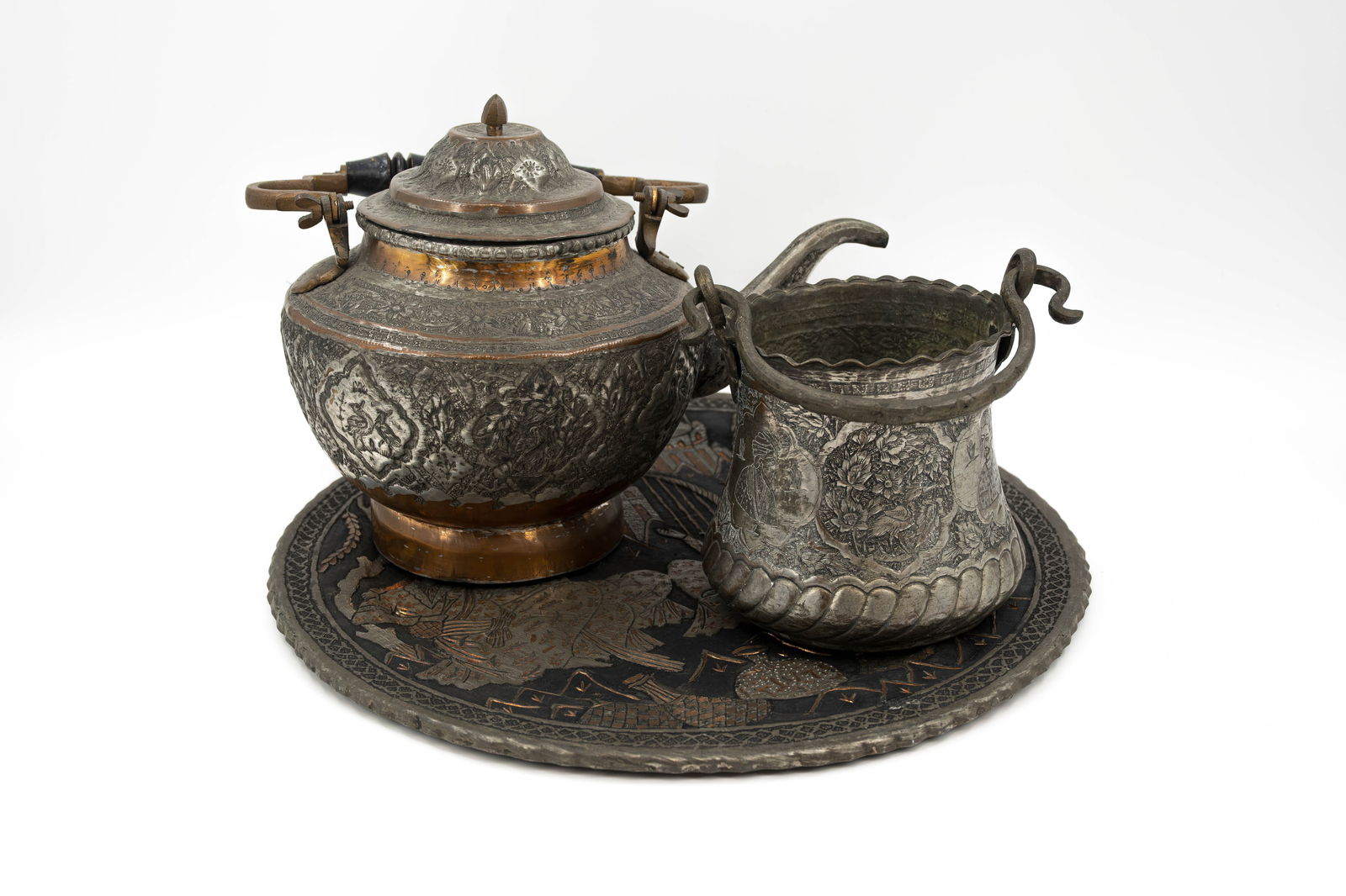 A lot of three antique Islamic Persian decorated tableware objects: A lot of three antique Islamic Persian decorated tableware objects. Consisting of one tea kettle, one pot with a handle and one round tray. 19th/20th century. H: 20 - 36 cm W: 48 cm