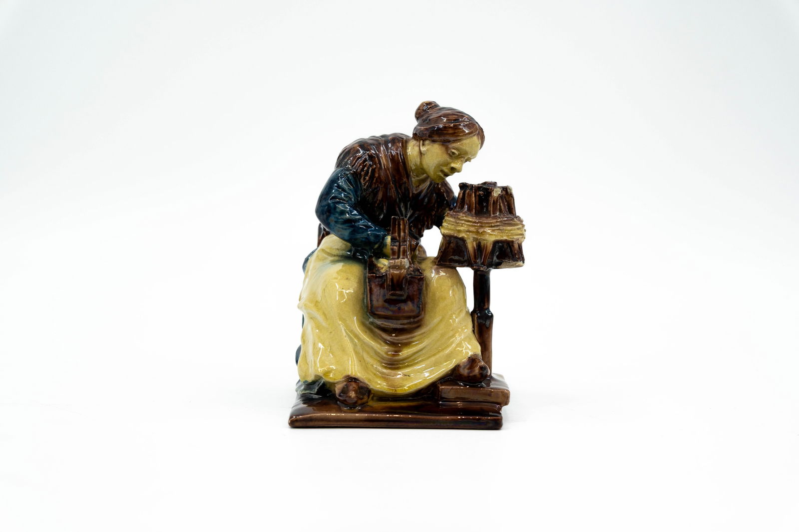 Achille VAN DE VOORDE (1875-1959) A Flemish Bruges glazed earthenware figure of a wool spinster: Achille VAN DE VOORDE (1875-1959) A Flemish Bruges glazed earthenware figure of a wool spinster. Signed, circa 1900-1920s. H: 15 cm