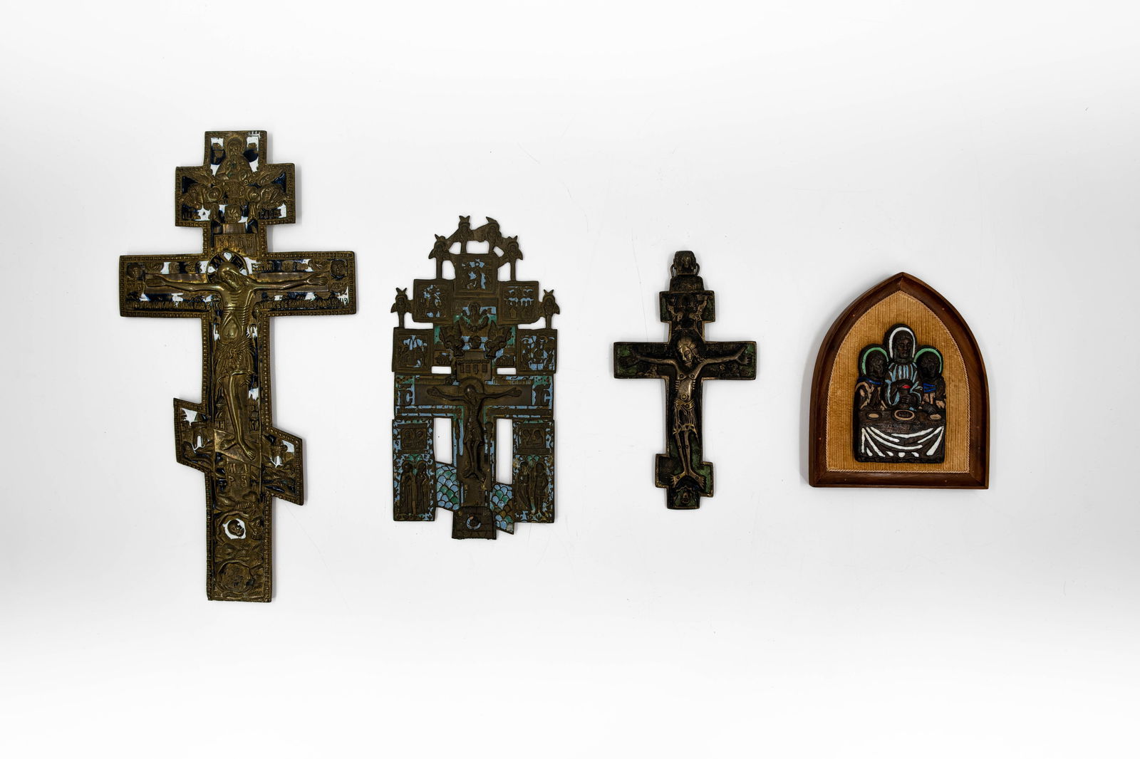 A lot of four antique Russian cast bronze crucifixes and wall objects: A lot of four antique Russian cast bronze crucifixes and wall objects with engraved details depicting the Crucifixion with God the Father and other saints. 19th century. H: 9,5 - 35,5 cm,