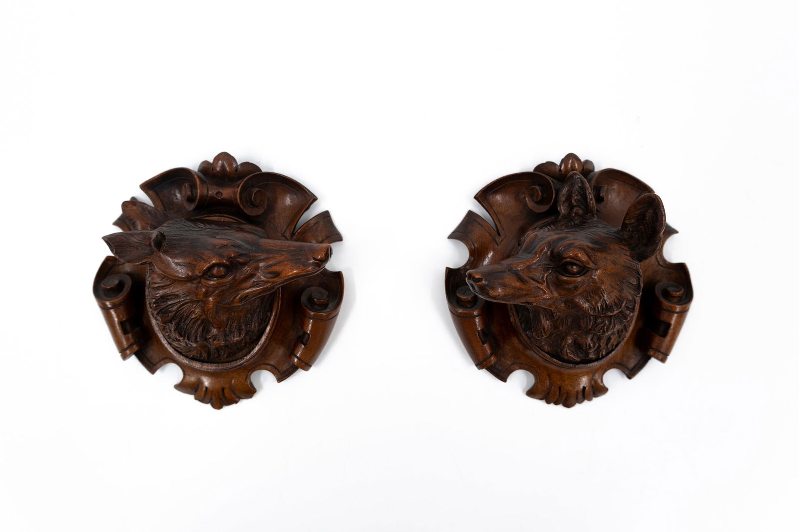 A pair of small and antique carved wooden black forest wall sculptures of two foxes: A pair of small and antique carved wooden black forest wall sculptures of two foxes. Circa 1900. H: 17 cm